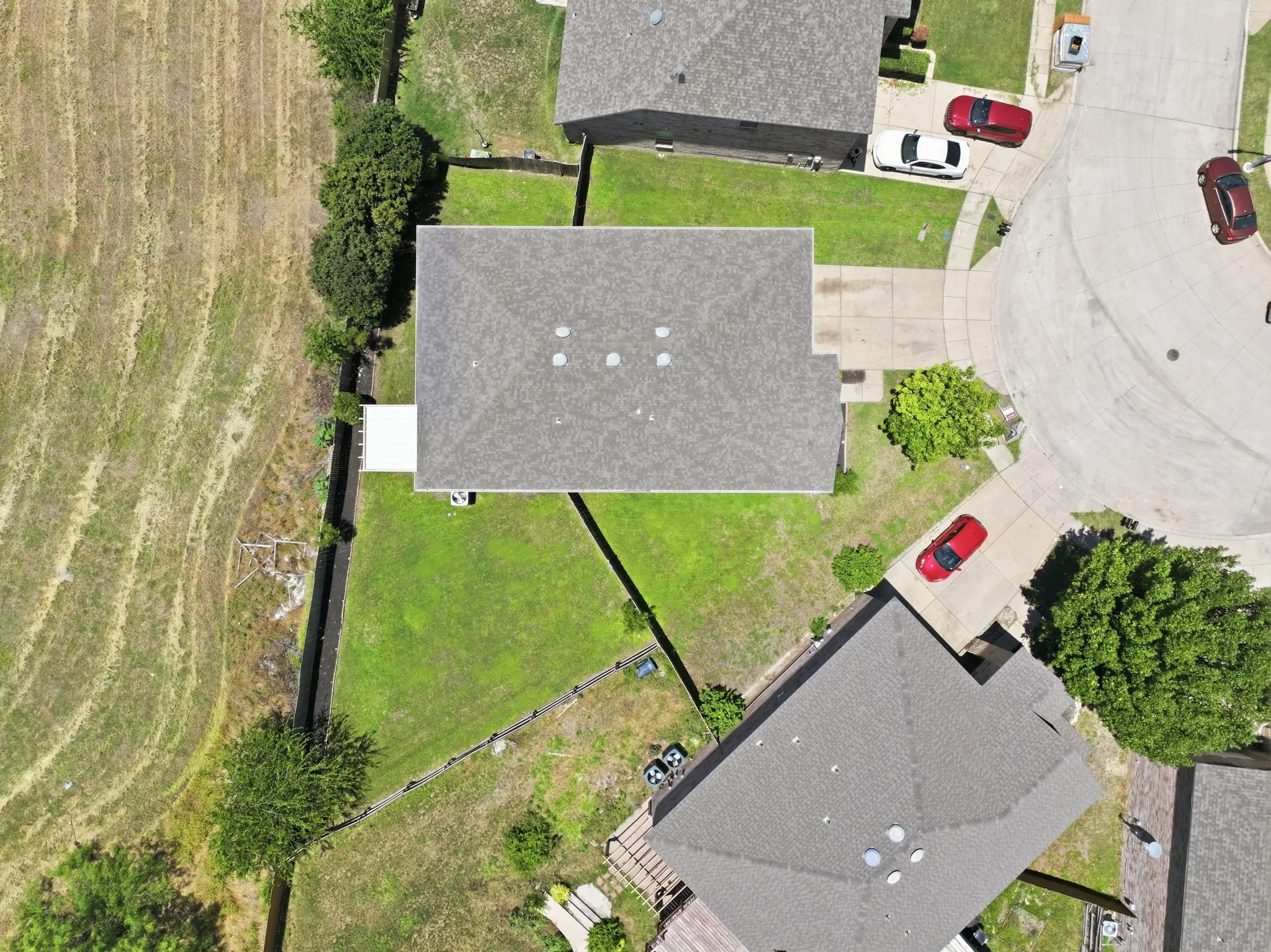 Property featuring a shingle roof, green lawn space, and a paved driveway