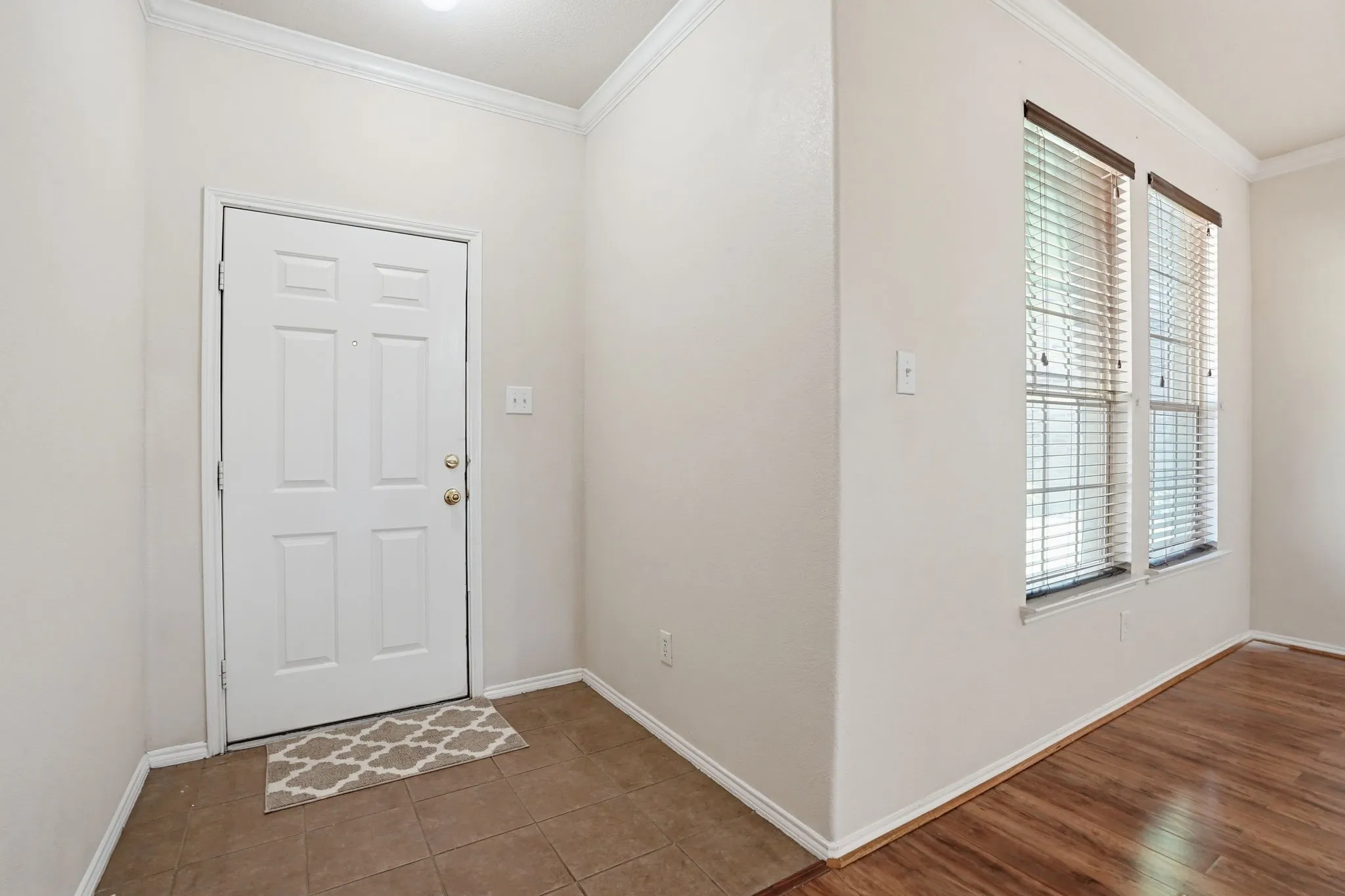 Front entryway featuring a paneled door, crown molding, and neutral wall tones
