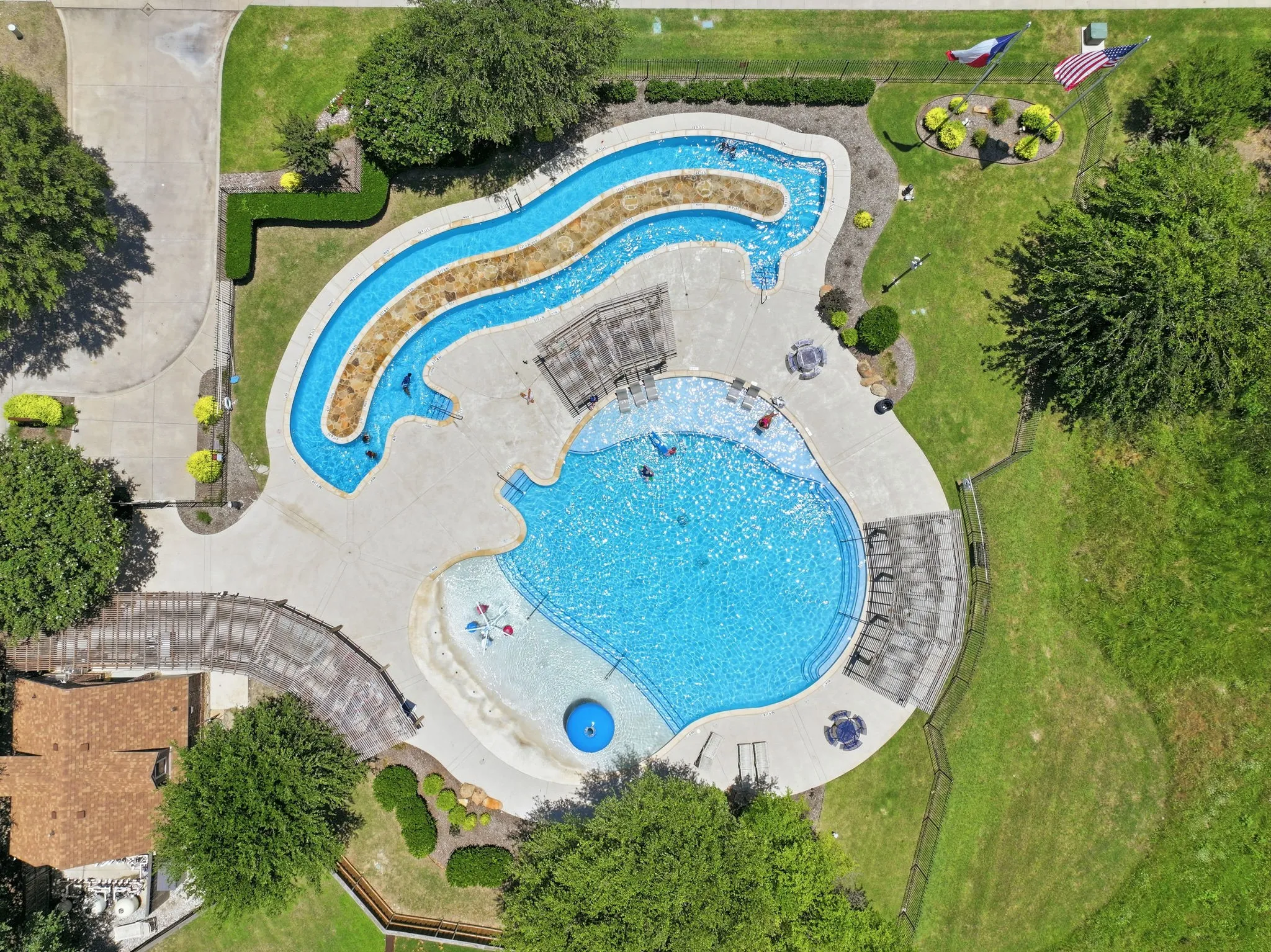 Expansive aquatic complex featuring a large swimming pool, meandering lazy river, and surrounding concrete deck. just down the street