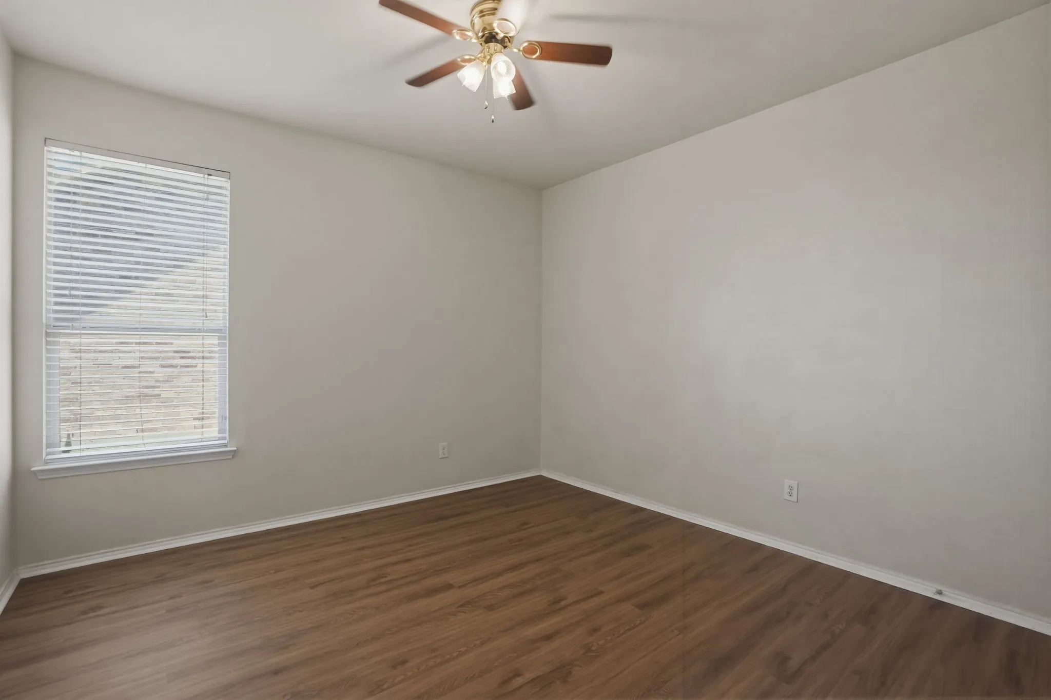 Room featuring wood-finish flooring, neutral wall tones, and a ceiling fan with light fixture