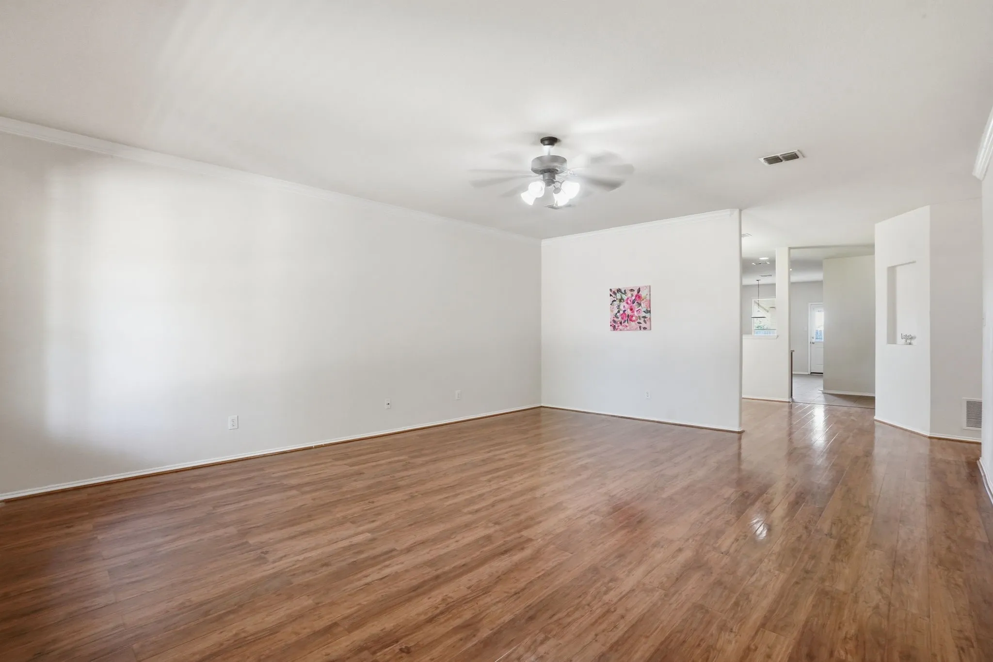 Living room featuring wood-finish flooring, white walls, and a ceiling fan with light fixture