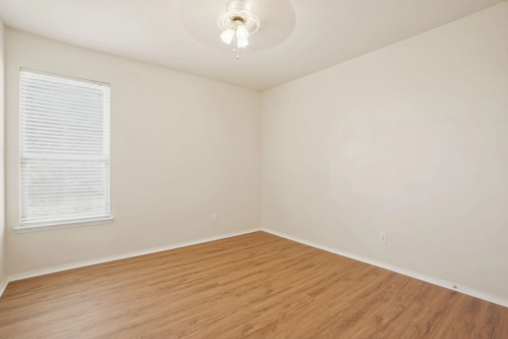 Room featuring wood-finish flooring, a window with blinds, and a ceiling fan with light fixture