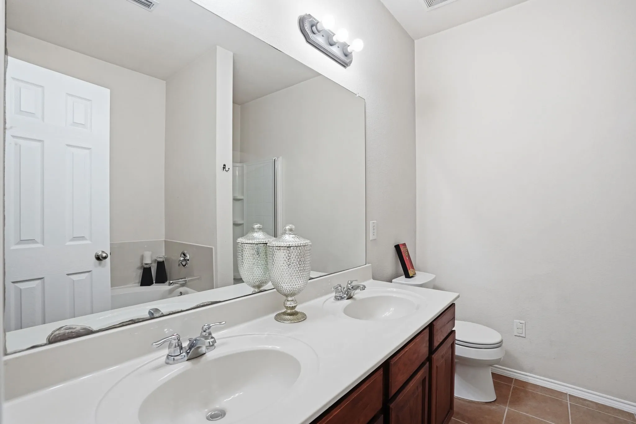 Bathroom featuring a dual-sink vanity with a white countertop and wood-finish cabinetry