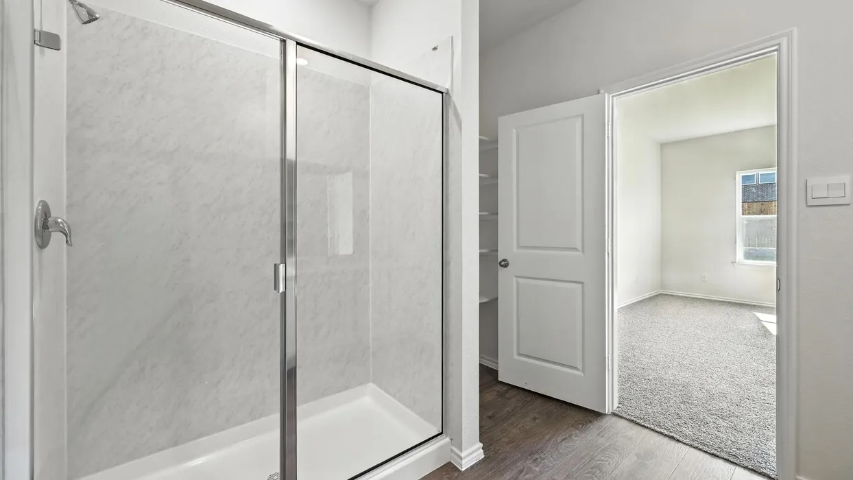 Walk-in shower with clear glass enclosure and chrome fixtures