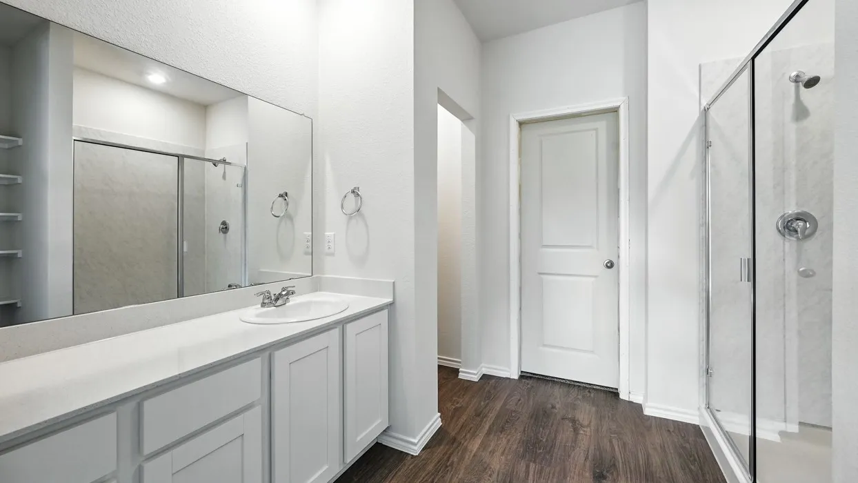 Bathroom featuring a vanity with an integrated sink, white cabinetry, and a large mirror