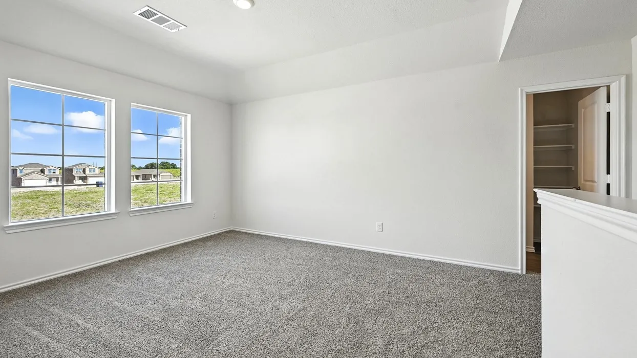 Spacious room featuring neutral carpeting, white walls, two large windows with grid patterns, a tray ceiling, and an open doorway revealing built-in shelving