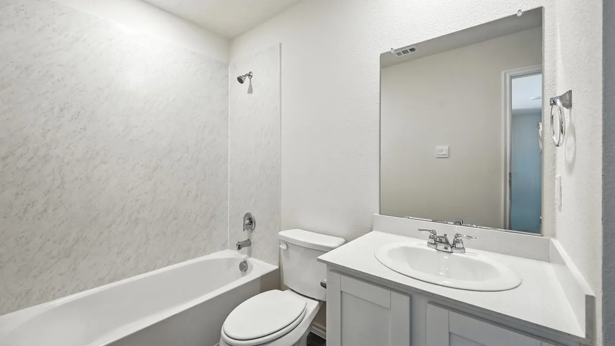 Full bathroom featuring a white tub, coordinating shower surround, and a white vanity with a single basin sink