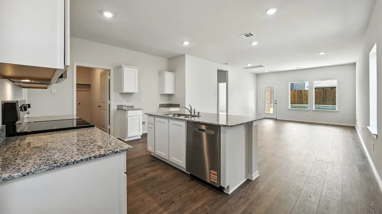 Open-concept kitchen and living area featuring white cabinetry, granite countertops, stainless steel appliances, and wood-finish flooring
