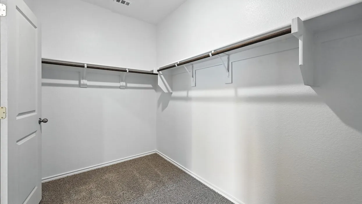 Walk-in closet featuring white walls, deep brown carpeting, and extensive built-in shelving with hanging rods