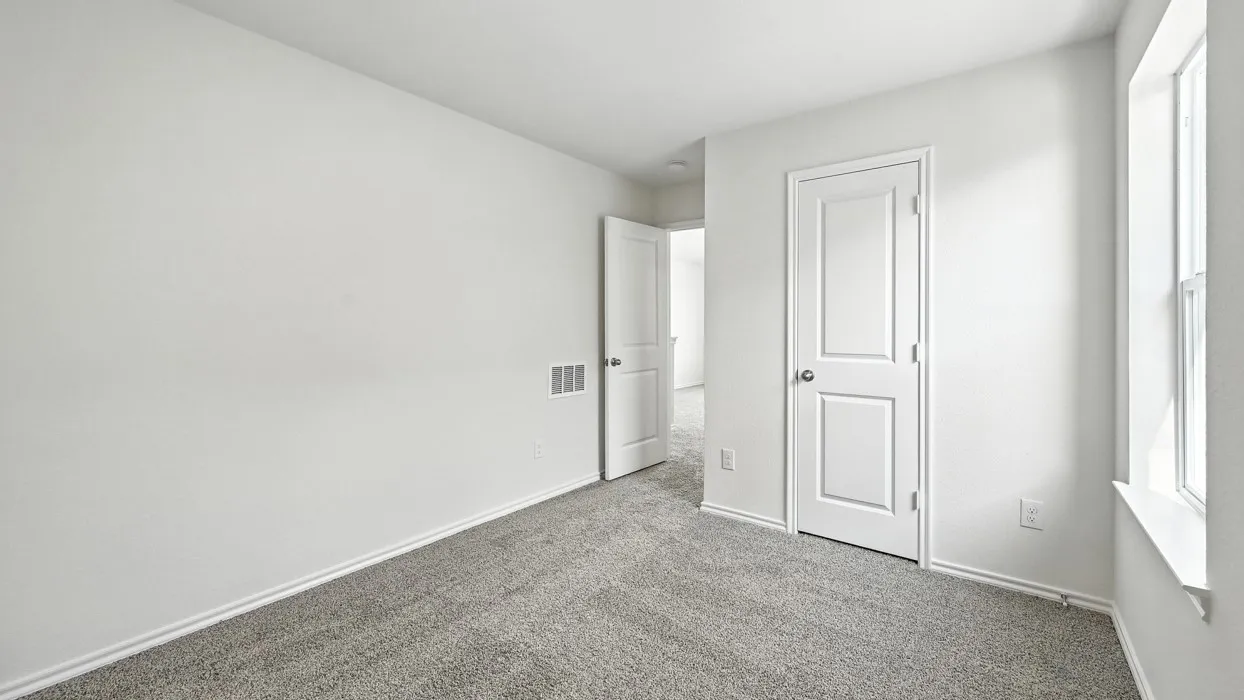Neutral-toned interior room featuring light gray carpeting and white trim