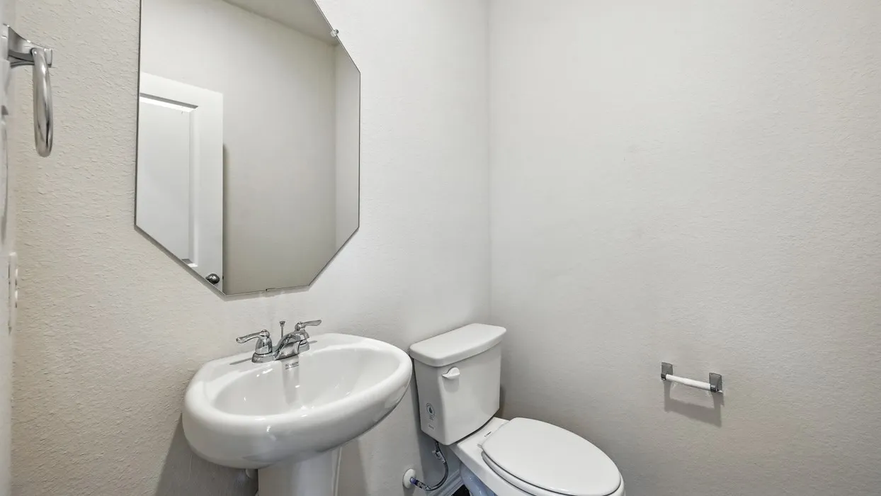 Pedestal sink with chrome fixtures and an octagonal mirror