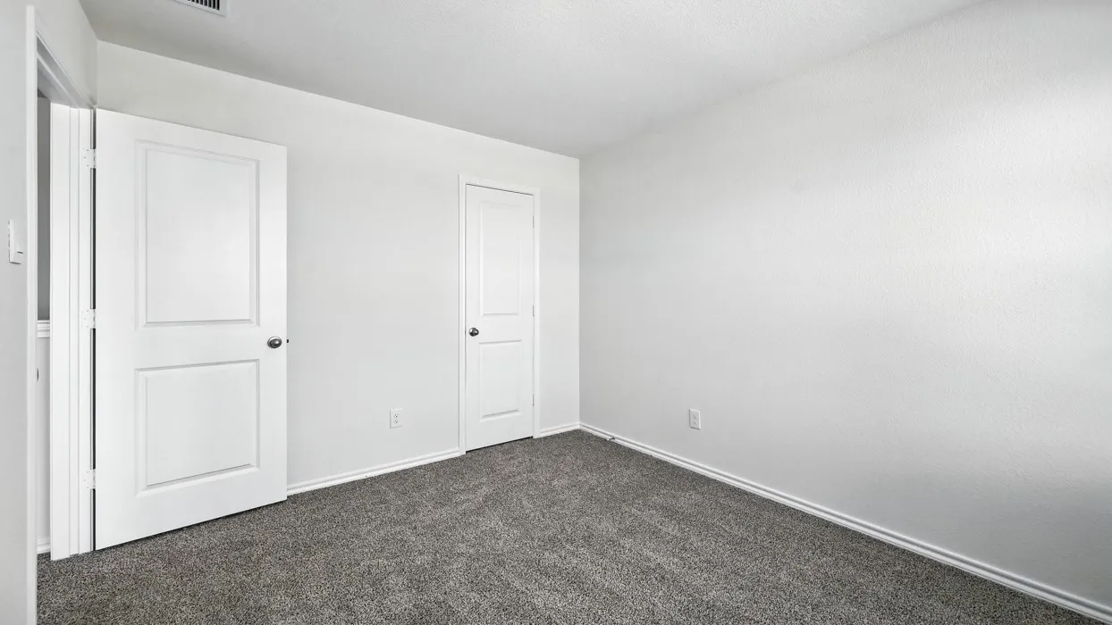 Neutral interior space featuring light-toned walls and dark gray carpeting