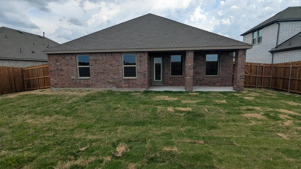 Expansive backyard featuring a covered patio, brick exterior, and new wood fencing