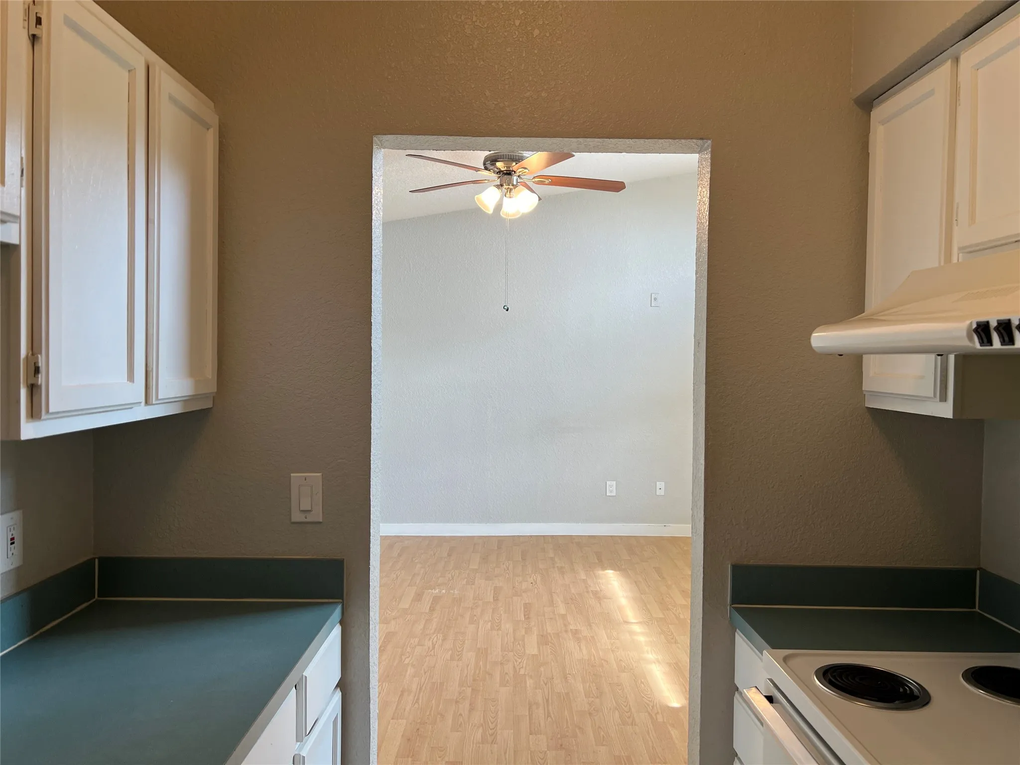 White cabinetry, solid surface countertops, and an electric range with an overhead hood