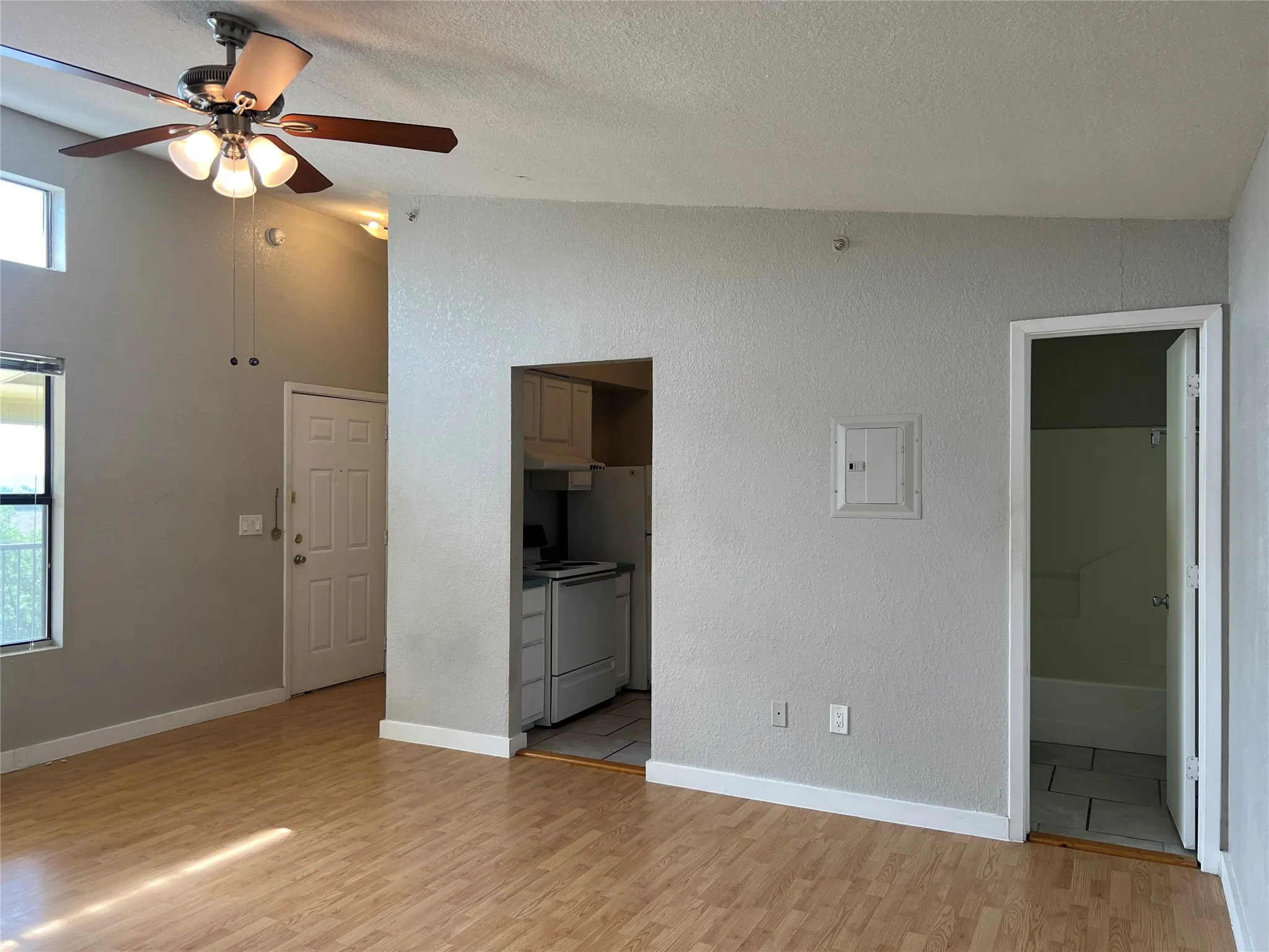 Vaulted ceiling with a ceiling fan, wood-finish flooring, and light gray painted walls