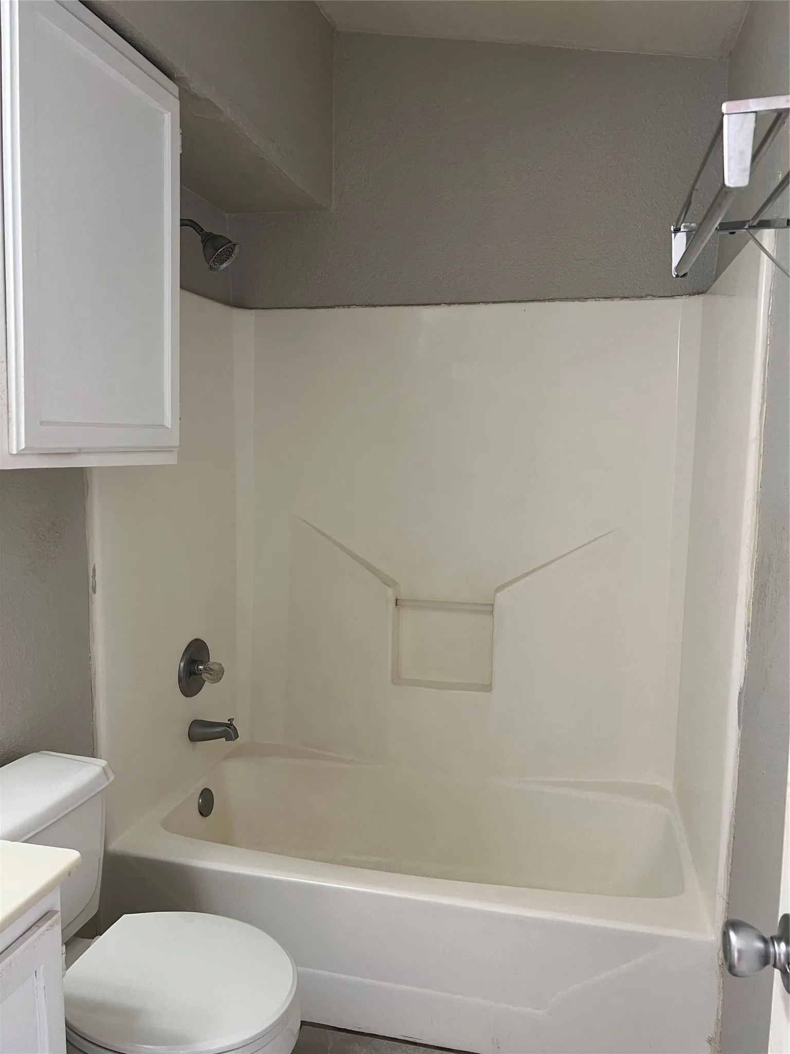White fiberglass tub and shower combination with chrome fixtures