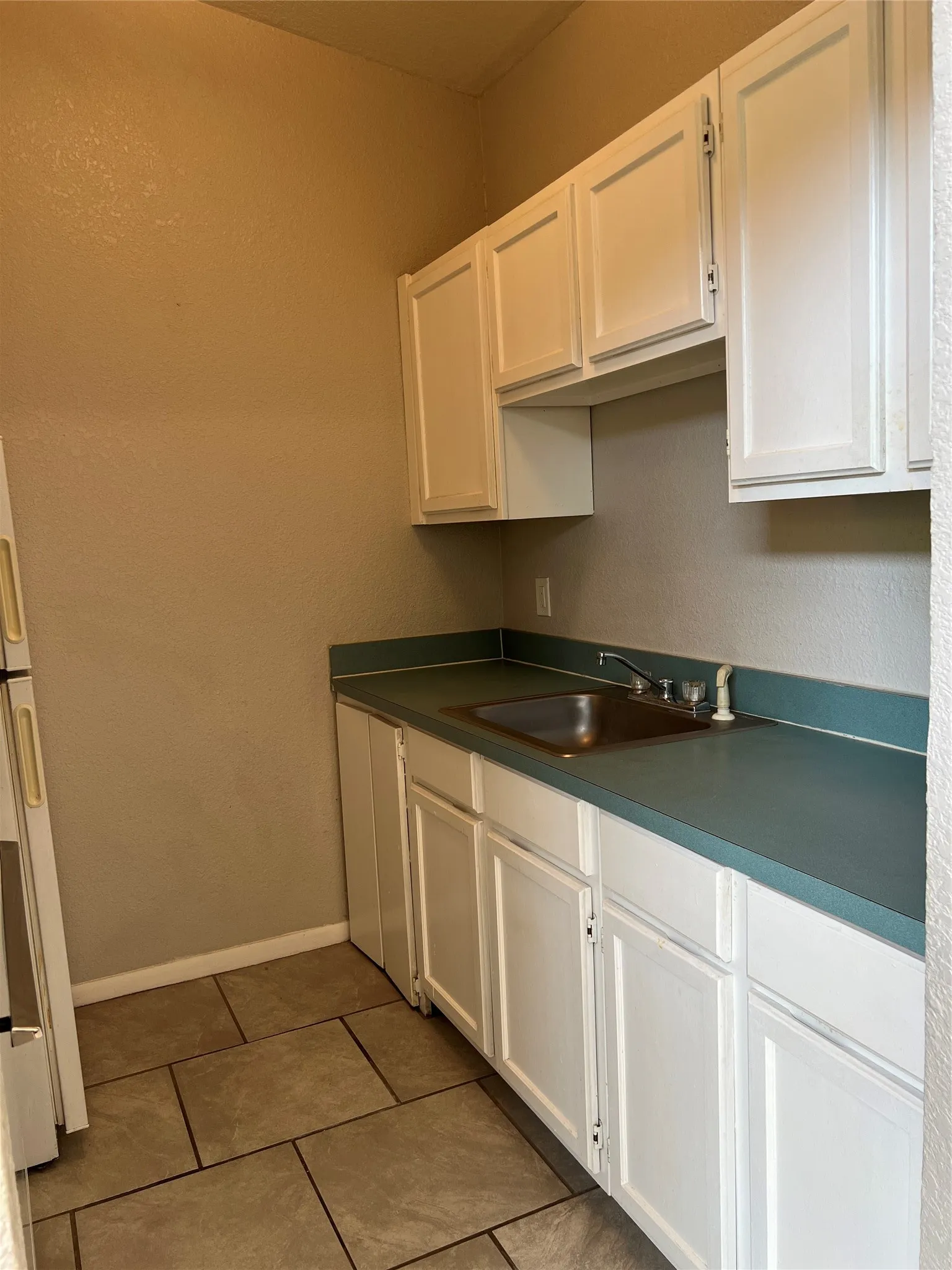 Kitchen featuring white cabinetry, a stainless steel sink, and durable countertops