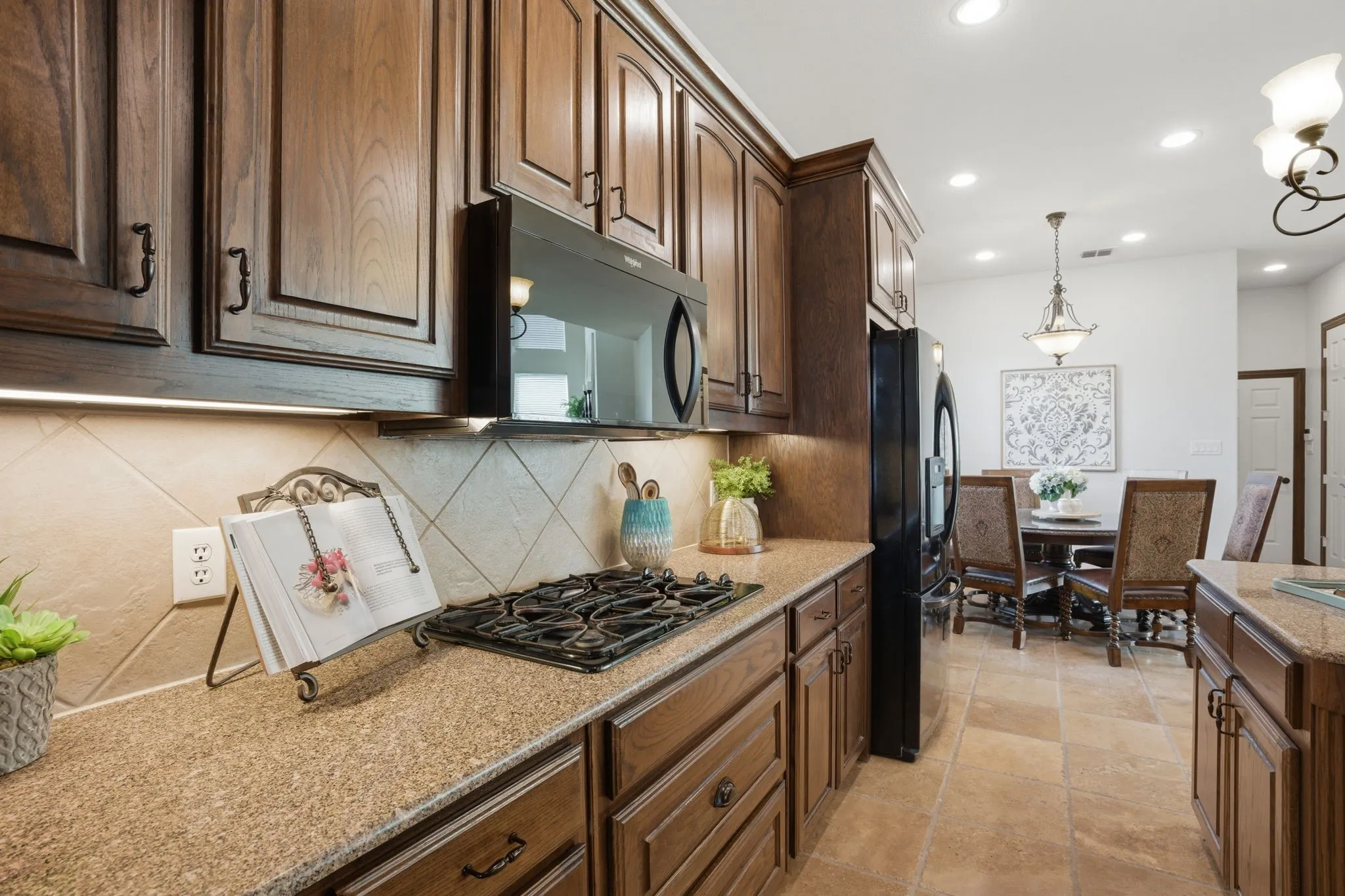 Kitchen appliances include a built-in GE double oven, a new built-in Whirlpool microwave, 4-burner GE gas cooktop, LG dishwasher, and a Kenmore Elite refrigerator that will convey with the home.