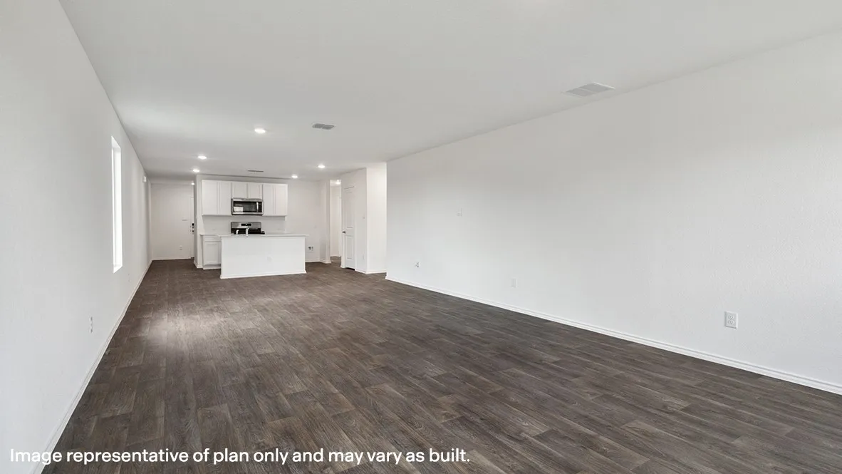 Spacious interior featuring wood-finish flooring, recessed lighting, and a kitchen with white cabinetry and an island