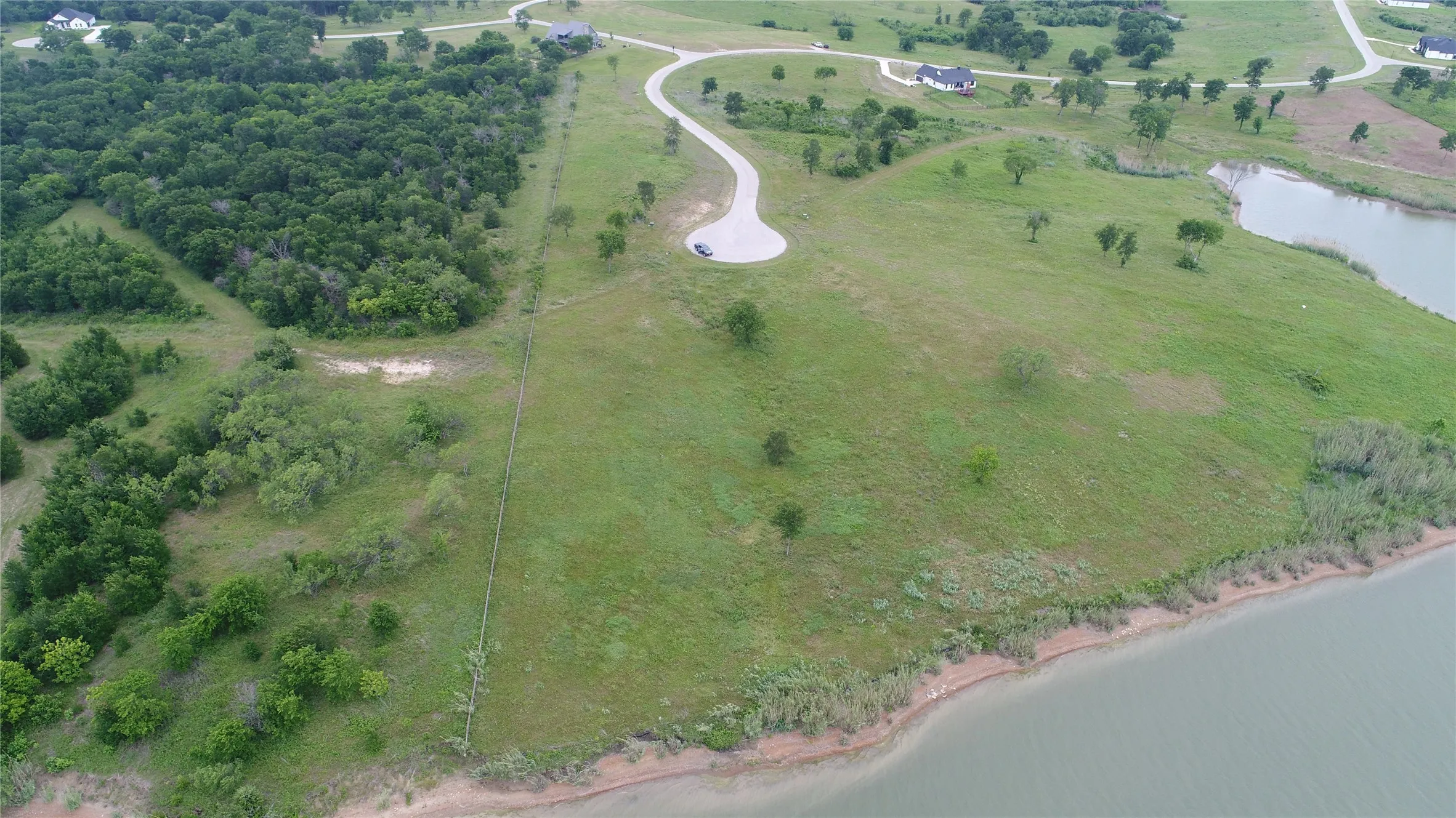 Expansive green space featuring a natural water body shoreline and mature trees
