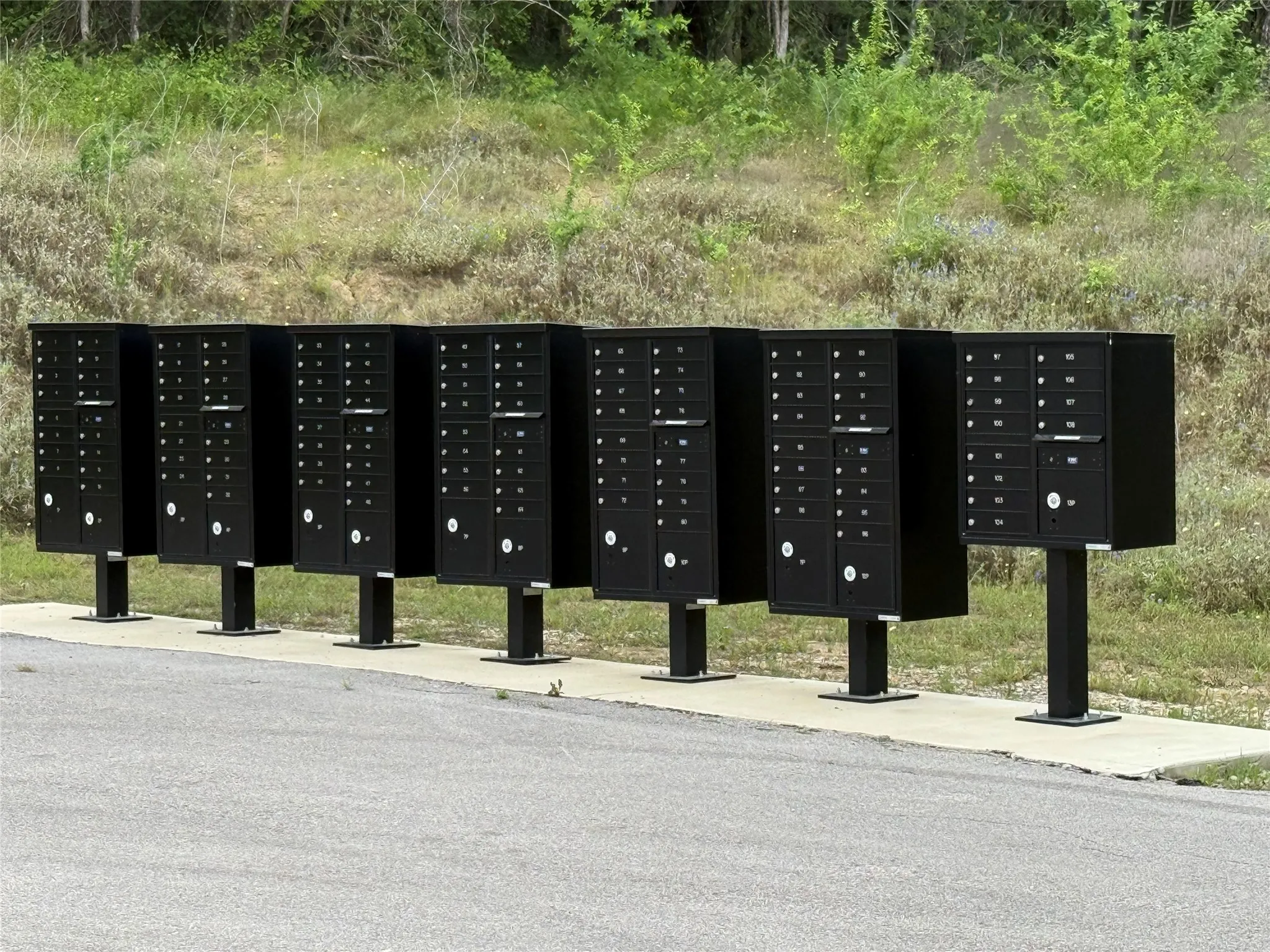 Centralized mailboxes on a concrete pad beside an asphalt surface
