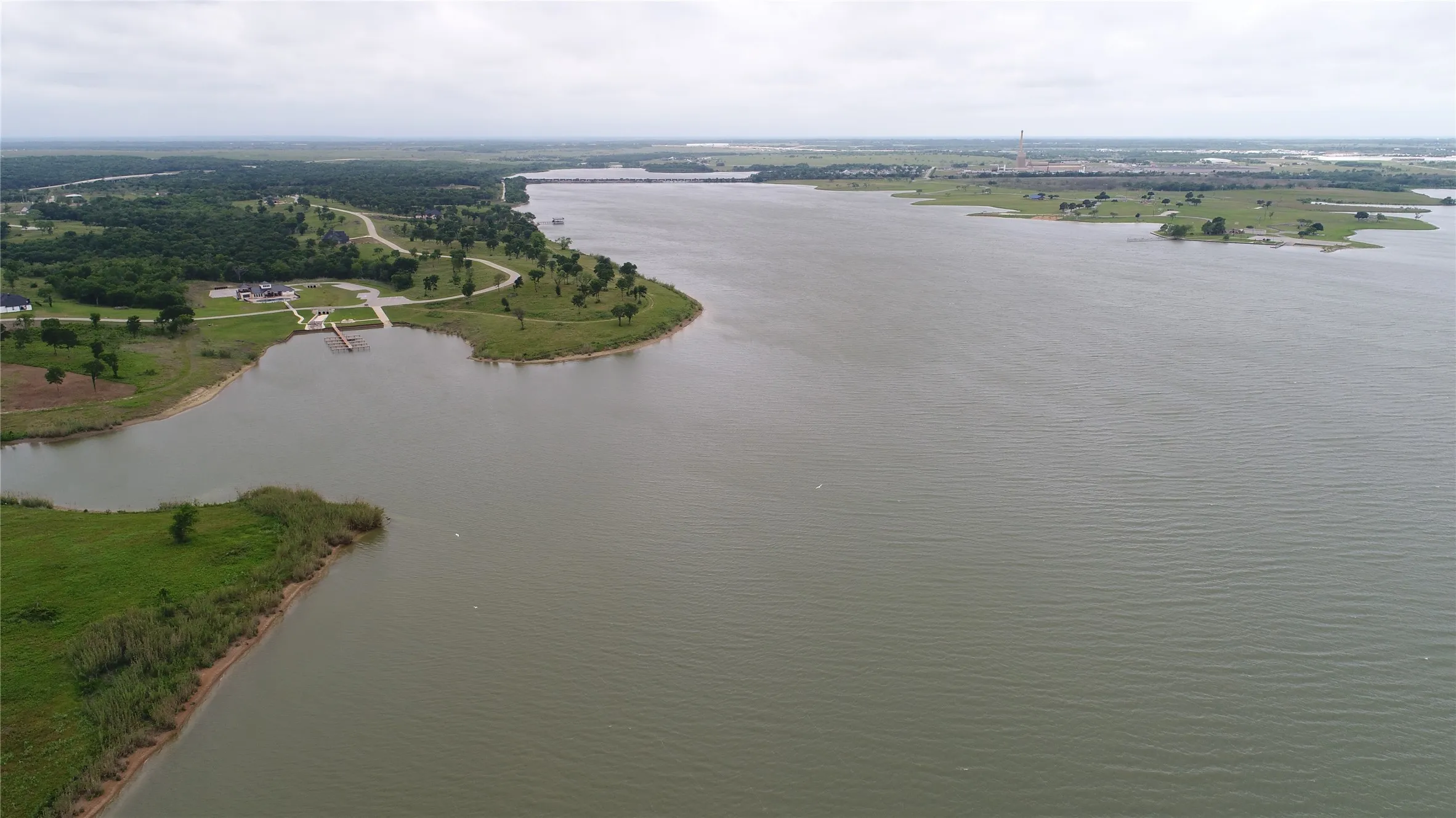 Expansive water frontage featuring a boat ramp, paved parking area, and mature trees along the shoreline