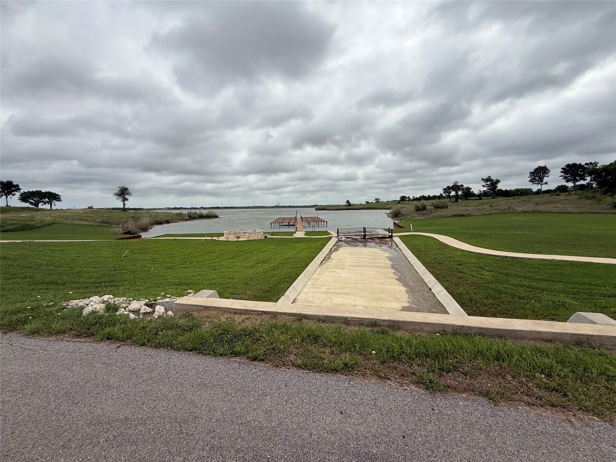 Waterfront property featuring a private boat ramp, an extensive dock, a manicured lawn, and mature trees along the shoreline