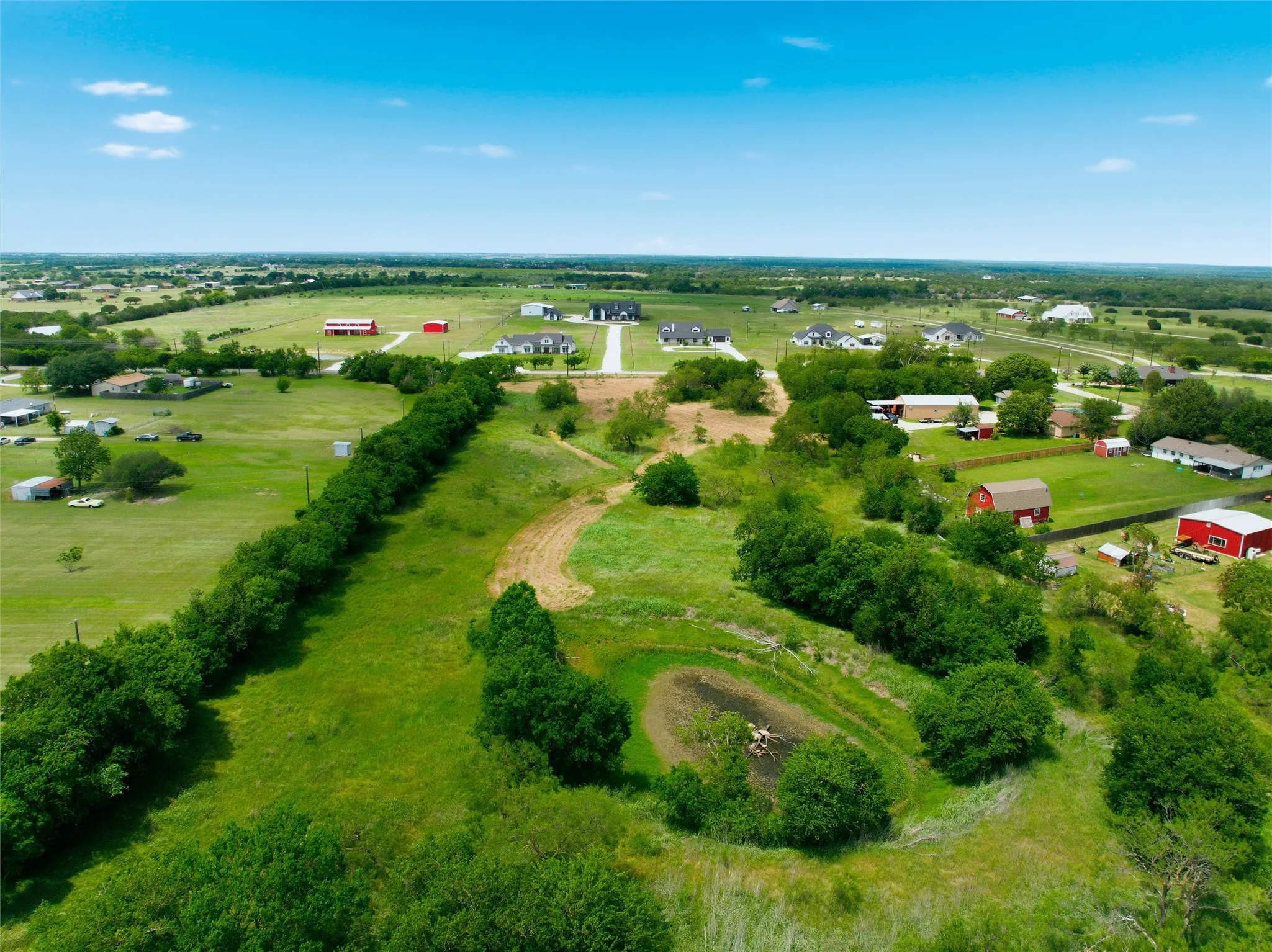 Expansive green landscape with a natural pond and varied topography