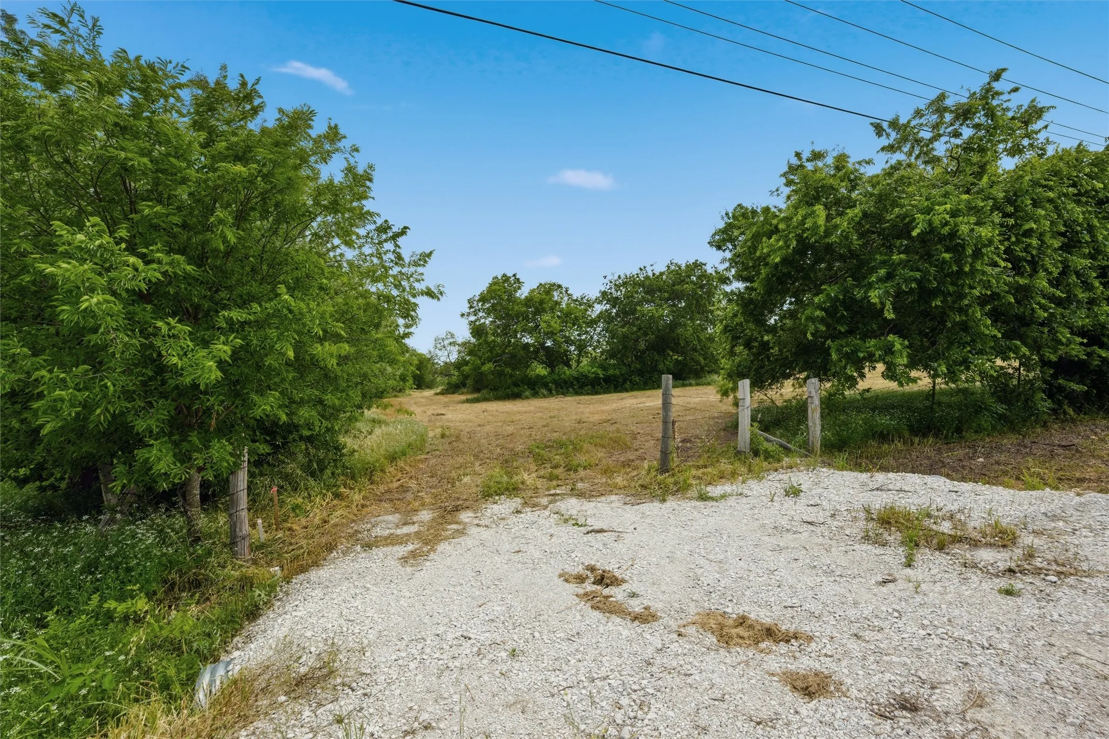 Expansive gravel entrance leading to an open land area