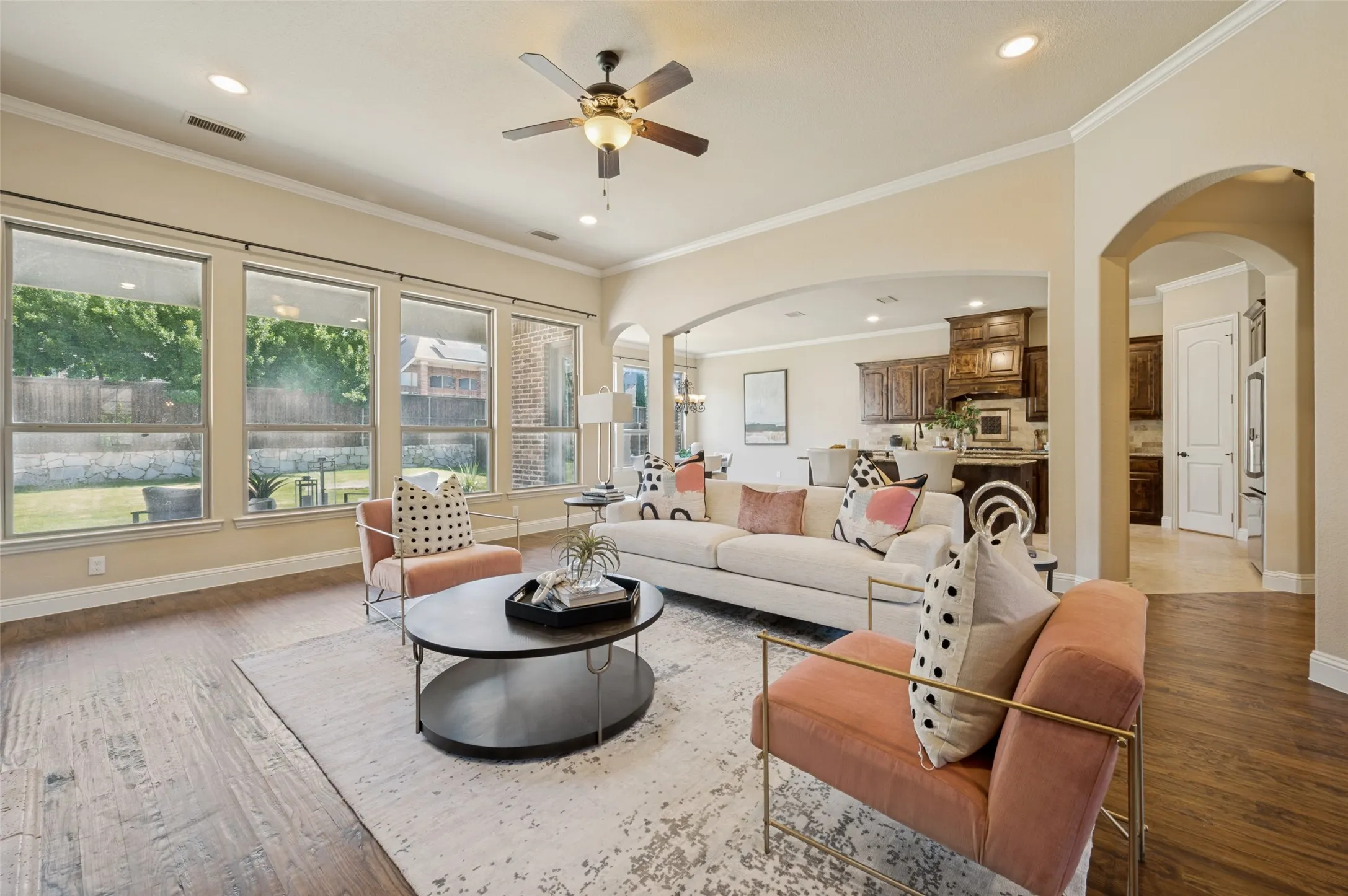 Designed for both grand entertaining and comfortable everyday living, this expansive family room offers soaring ceilings, rich hardwood floors, and an open-concept layout that flows seamlessly into the chef's kitchen and breakfast area. Walls of oversized windows bathe the space in natural light while showcasing peaceful backyard views, creating the perfect setting for gathering with family and friends.
