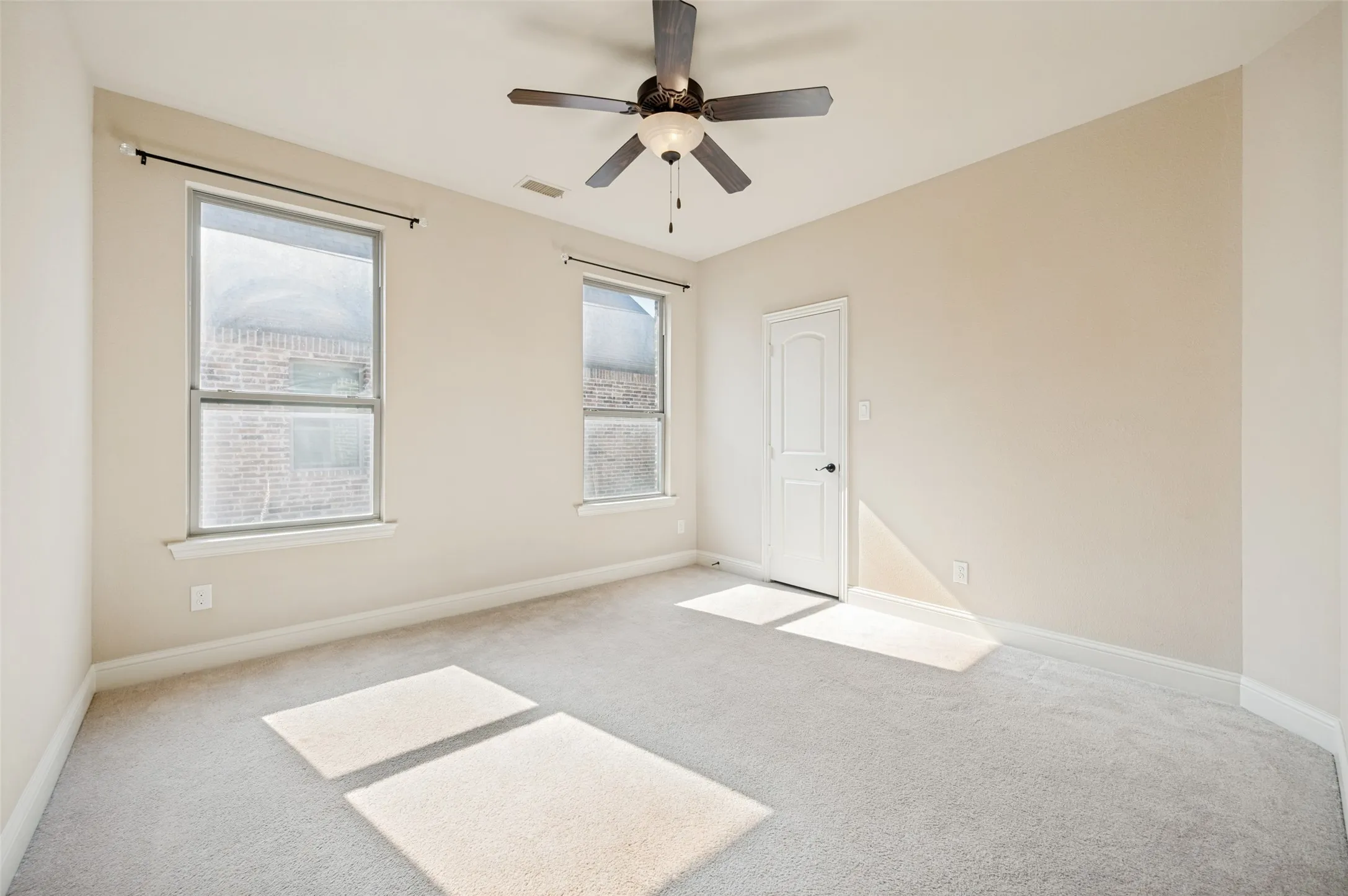 Bright and inviting secondary bedroom featuring plush carpet, a ceiling fan, and abundant natural light. Conveniently located near the shared full bathroom, this versatile space is perfect for family, guests, or a home office.