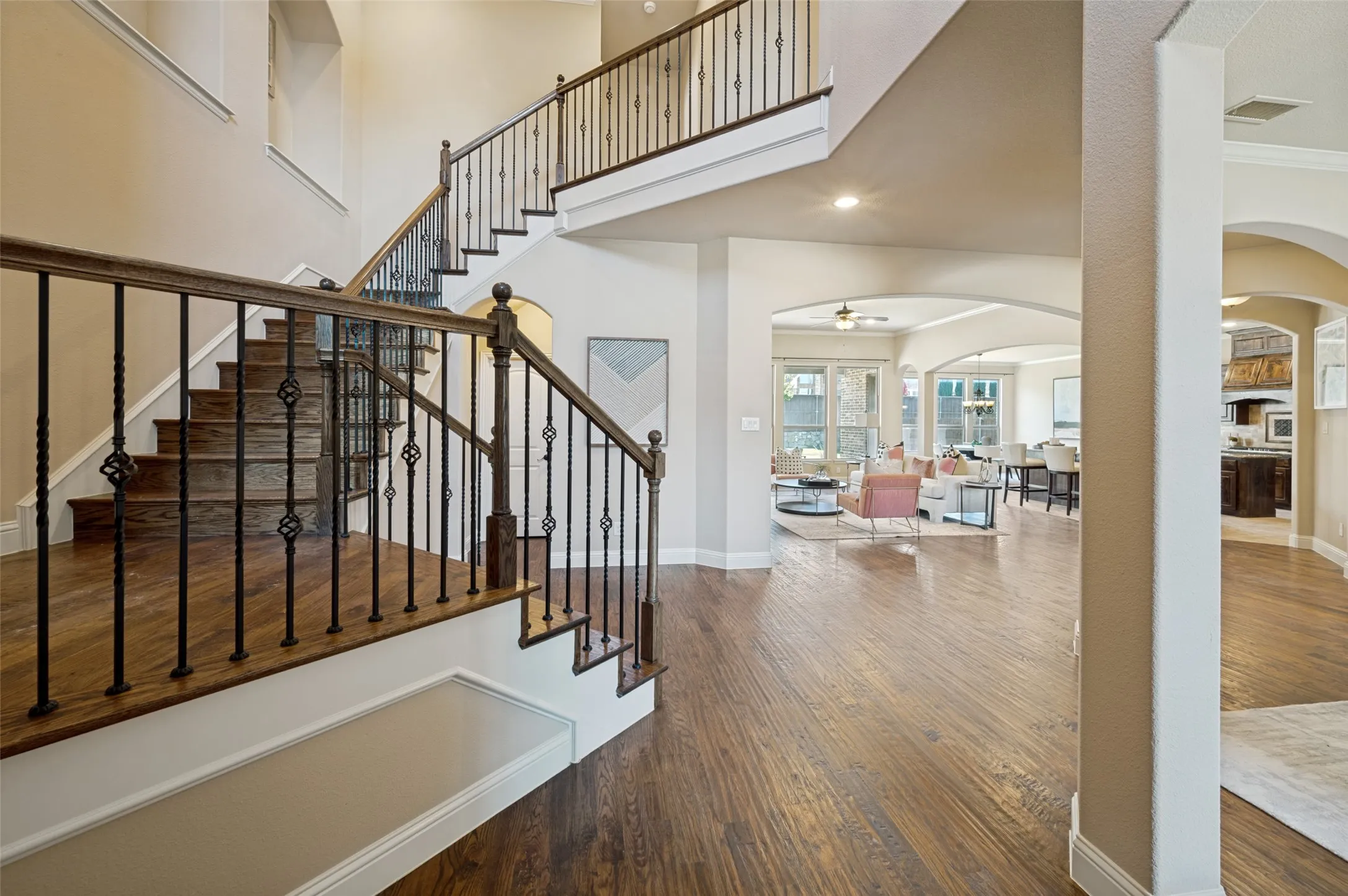 From the moment you step inside, you're welcomed by soaring ceilings, rich hardwood floors, and an elegant staircase with wrought-iron balusters that create a grand sense of arrival. The open-concept design seamlessly connects the home's spacious living areas while showcasing timeless architectural details and abundant natural light throughout.