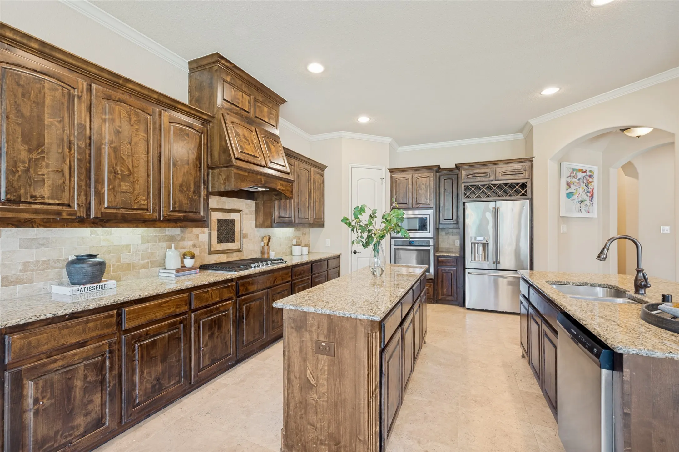 A true culinary masterpiece, this luxury chef's kitchen is the centerpiece of the home, featuring rich custom cabinetry, dual oversized granite islands, double ovens, a gas cooktop beneath a handcrafted vent hood, stainless steel appliances, and an abundance of workspace and storage. Thoughtfully designed for grand entertaining and everyday living, this elegant space seamlessly connects to the main living areas, making it the perfect gathering place for family and guests.