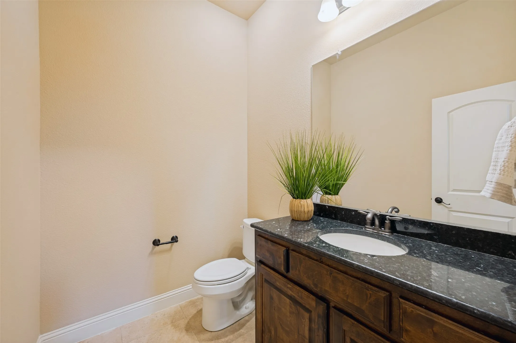 Convenient first-floor powder bath featuring a granite-topped vanity, rich wood cabinetry, and timeless finishes. Perfectly positioned for guests, this well-appointed half bath blends style and functionality for everyday living and entertaining.