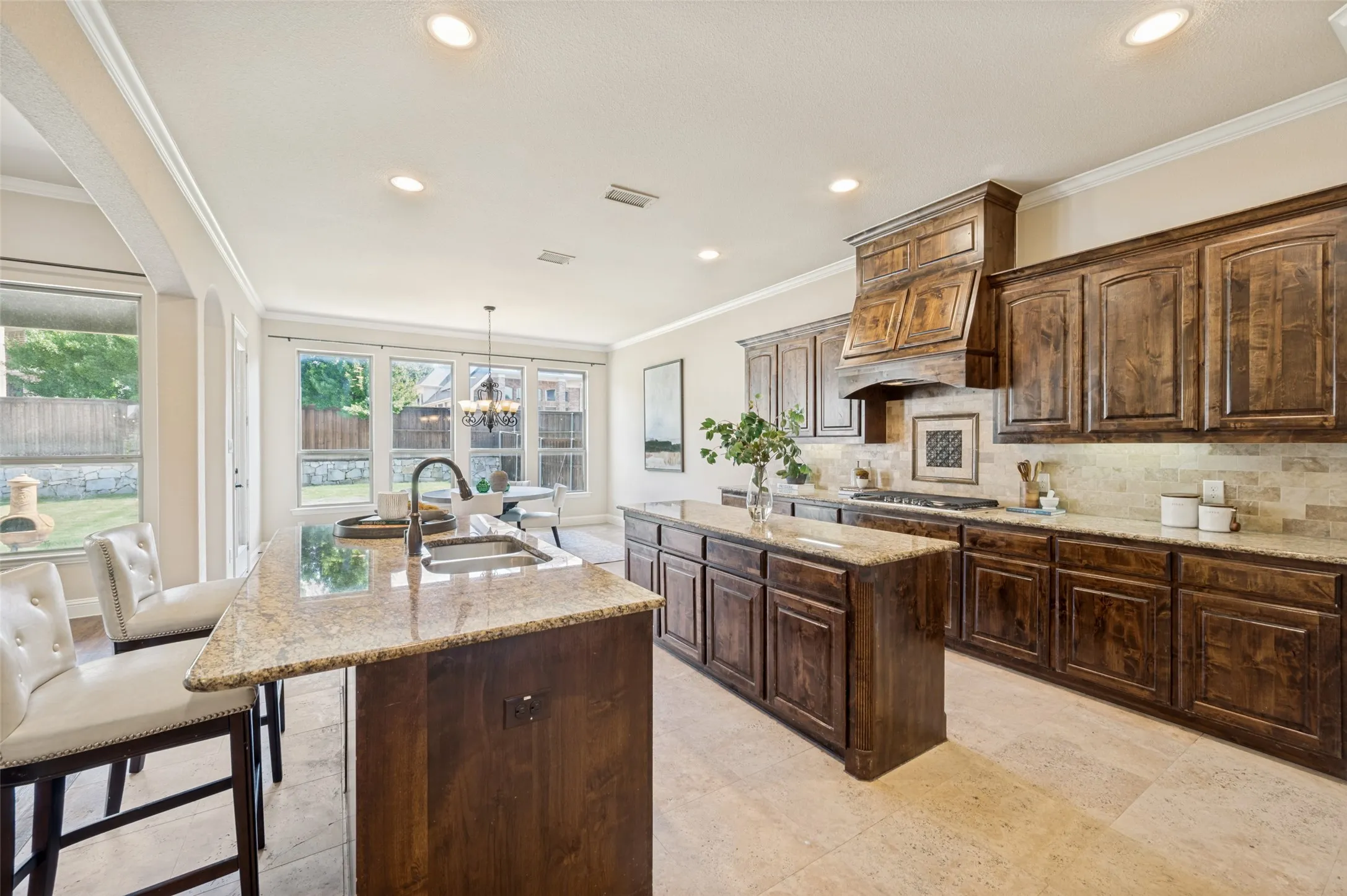The heart of the home, this stunning chef's kitchen is designed to impress with rich custom cabinetry, dual oversized granite islands, double ovens, a gas cooktop with a custom vent hood, stainless steel appliances, and abundant storage. Open to the breakfast area and family room, this exceptional space blends luxury, functionality, and effortless entertaining while overlooking the private backyard.