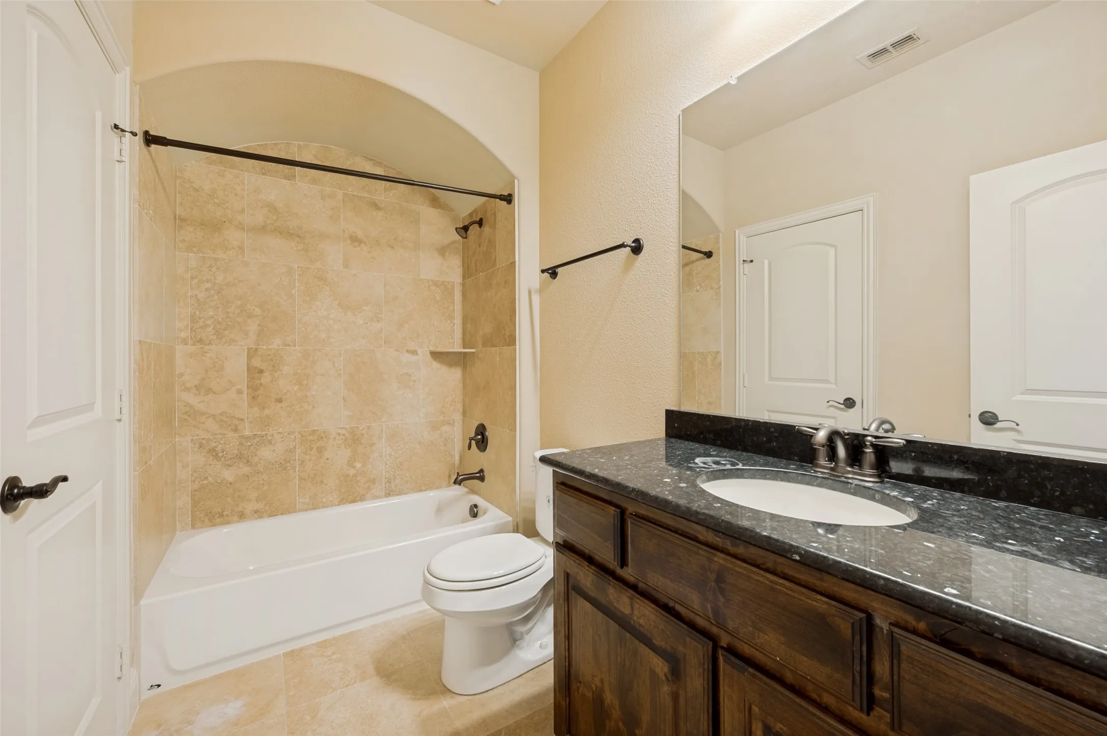 Well-appointed shared full bathroom featuring a granite-topped vanity with rich wood cabinetry, elegant tile flooring, and a tiled tub/shower combination. Conveniently located between the secondary bedrooms, this thoughtfully designed bath offers both style and functionality for family and guests.