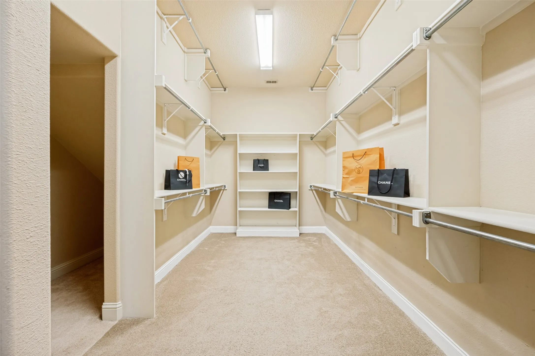 Expansive walk-in primary closet thoughtfully designed with abundant hanging space, built-in shelving, and room for every wardrobe essential. This oversized closet offers exceptional organization and storage, making it a perfect extension of the luxurious primary suite.