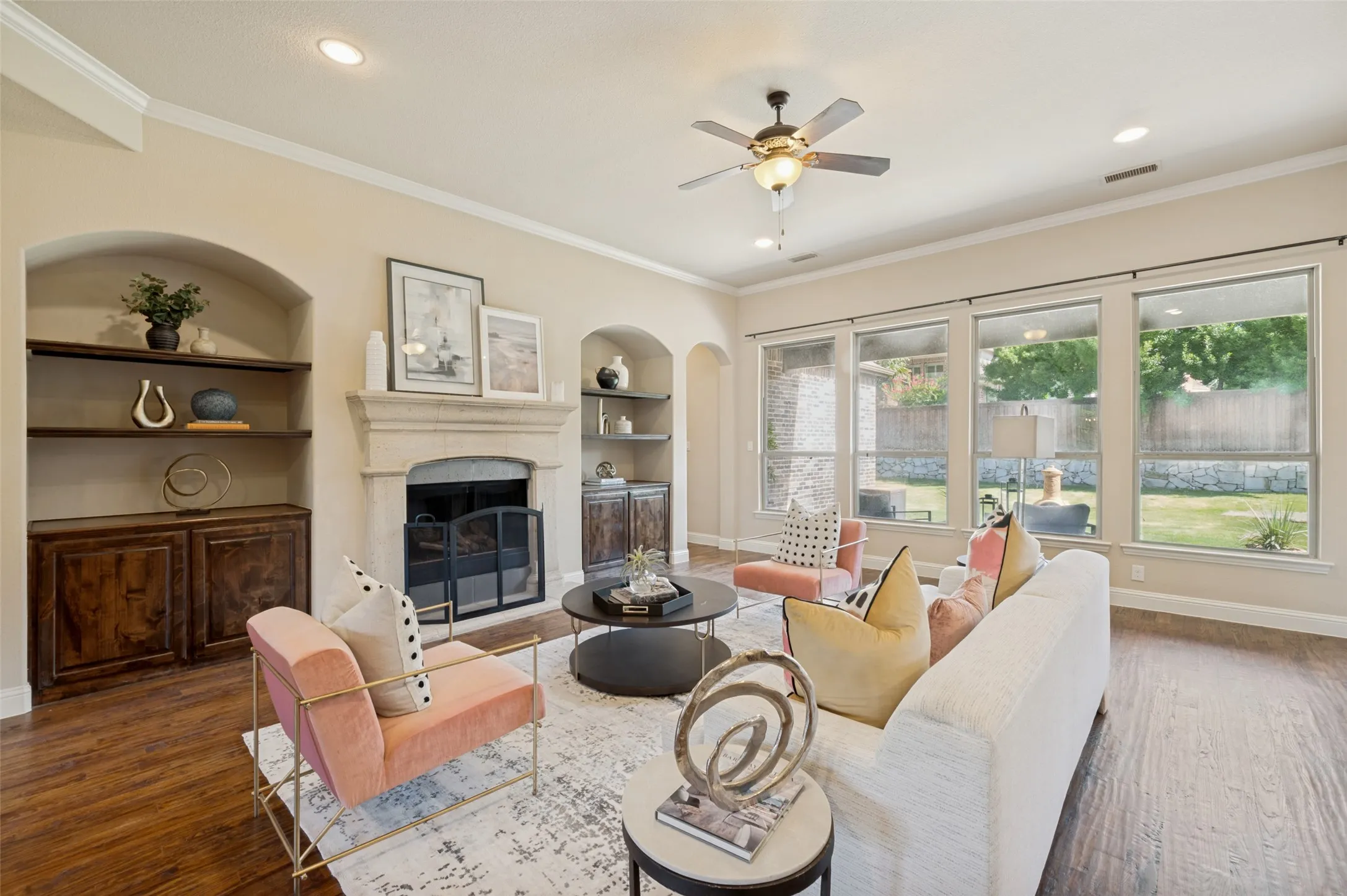 The inviting family room is the heart of the home, showcasing rich hardwood floors, a stunning floor-to-ceiling stone fireplace, custom built-in cabinetry, and a wall of oversized windows that fill the space with natural light. Thoughtfully designed for both everyday living and effortless entertaining, this open-concept gathering space seamlessly connects to the chef's kitchen while offering peaceful views of the backyard.