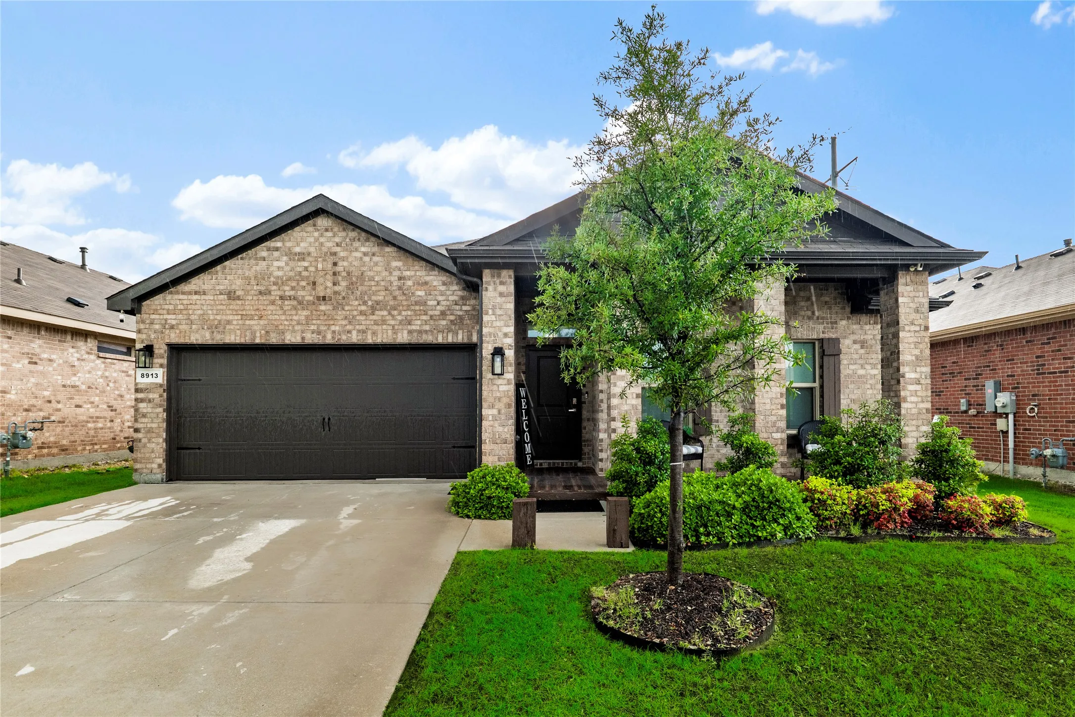 Brick exterior with dark trim and a two-car garage