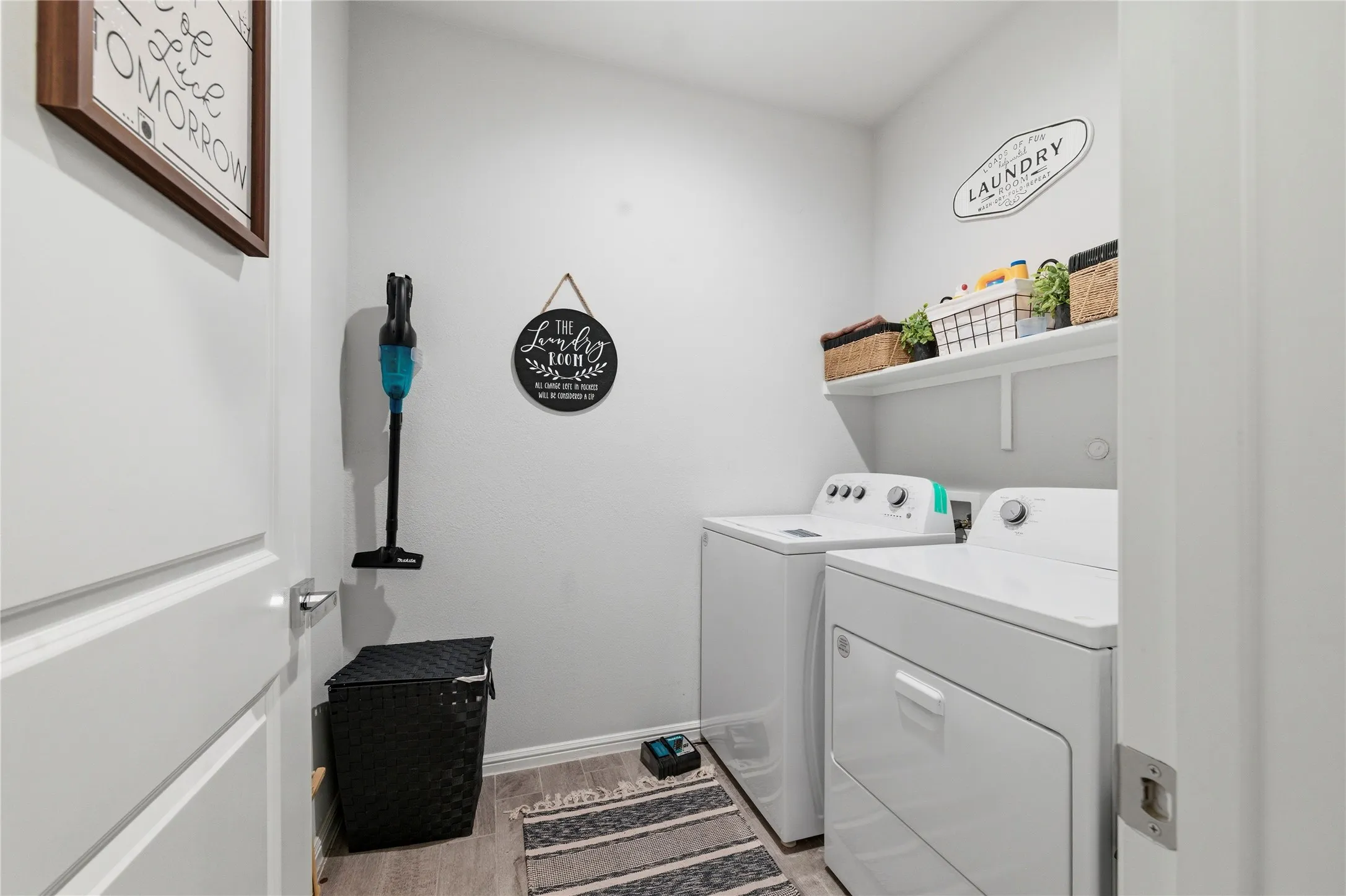 Dedicated laundry area featuring a built-in shelving unit, wood-finish flooring, and light-toned walls