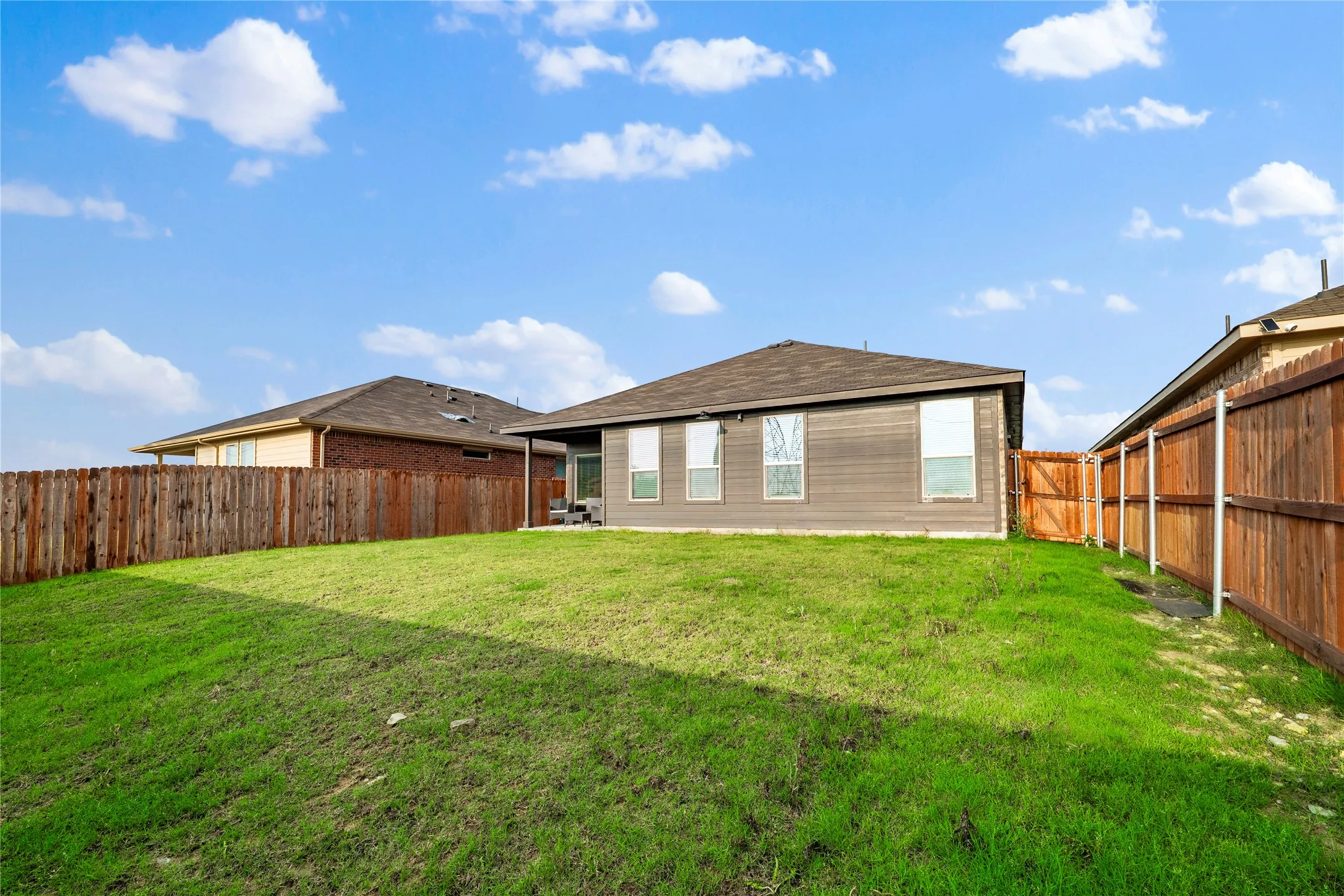 Expansive grassy backyard featuring a full privacy fence