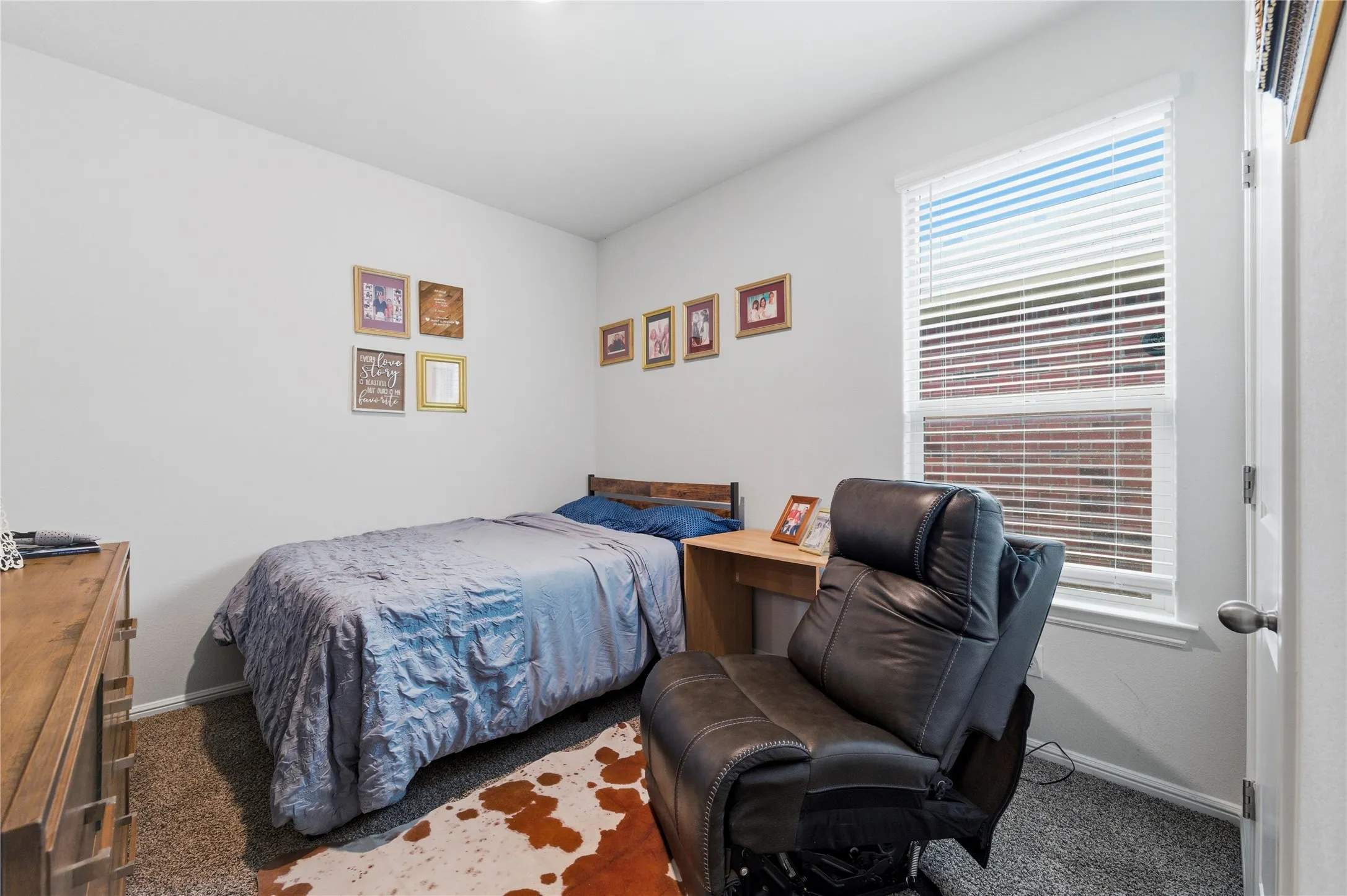 Carpeted room featuring a single window with blinds, light-colored walls, and a white door with a round knob