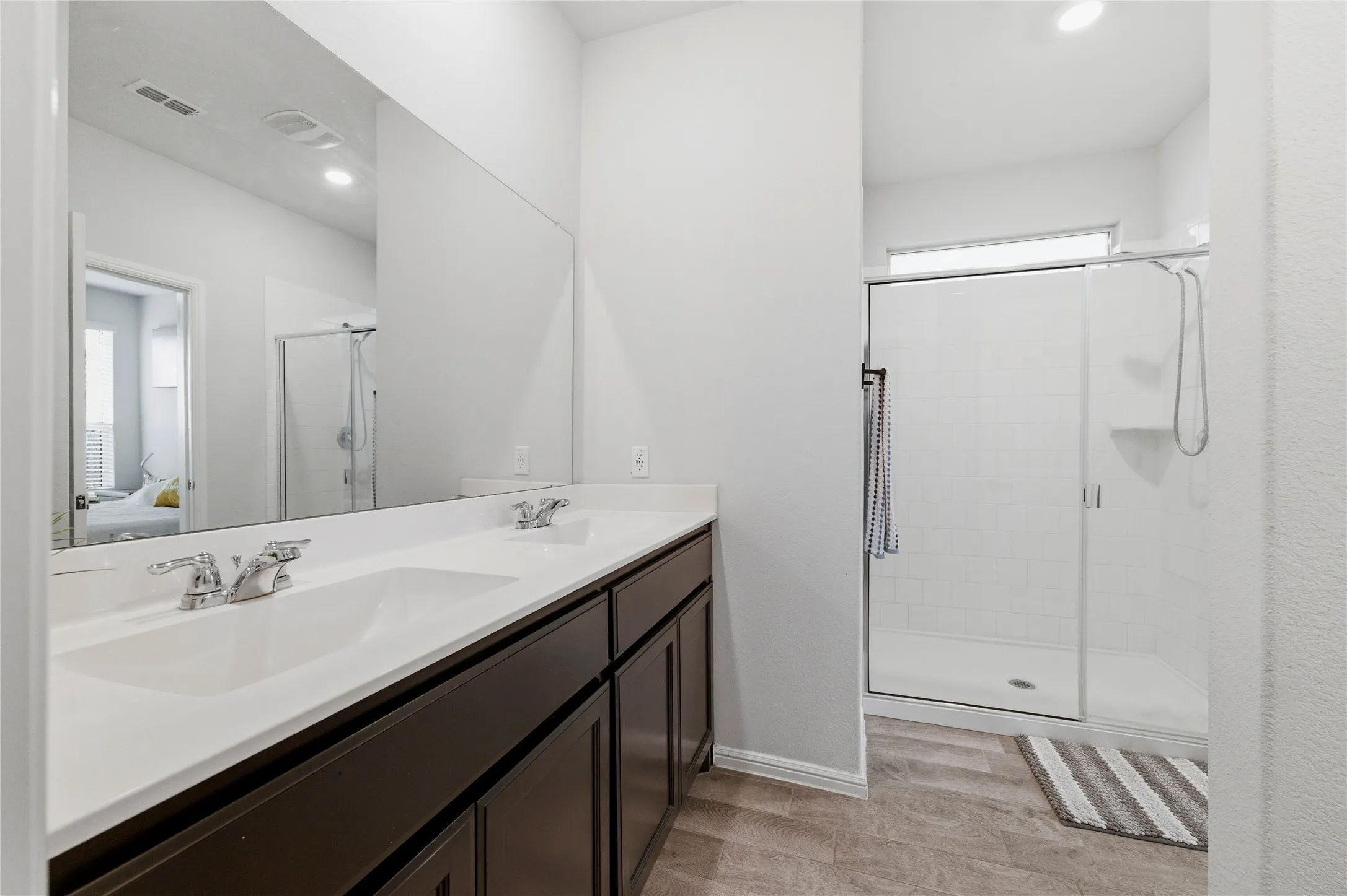 Bathroom featuring a dual vanity with white countertops, dark wood-finish cabinetry, and chrome fixtures