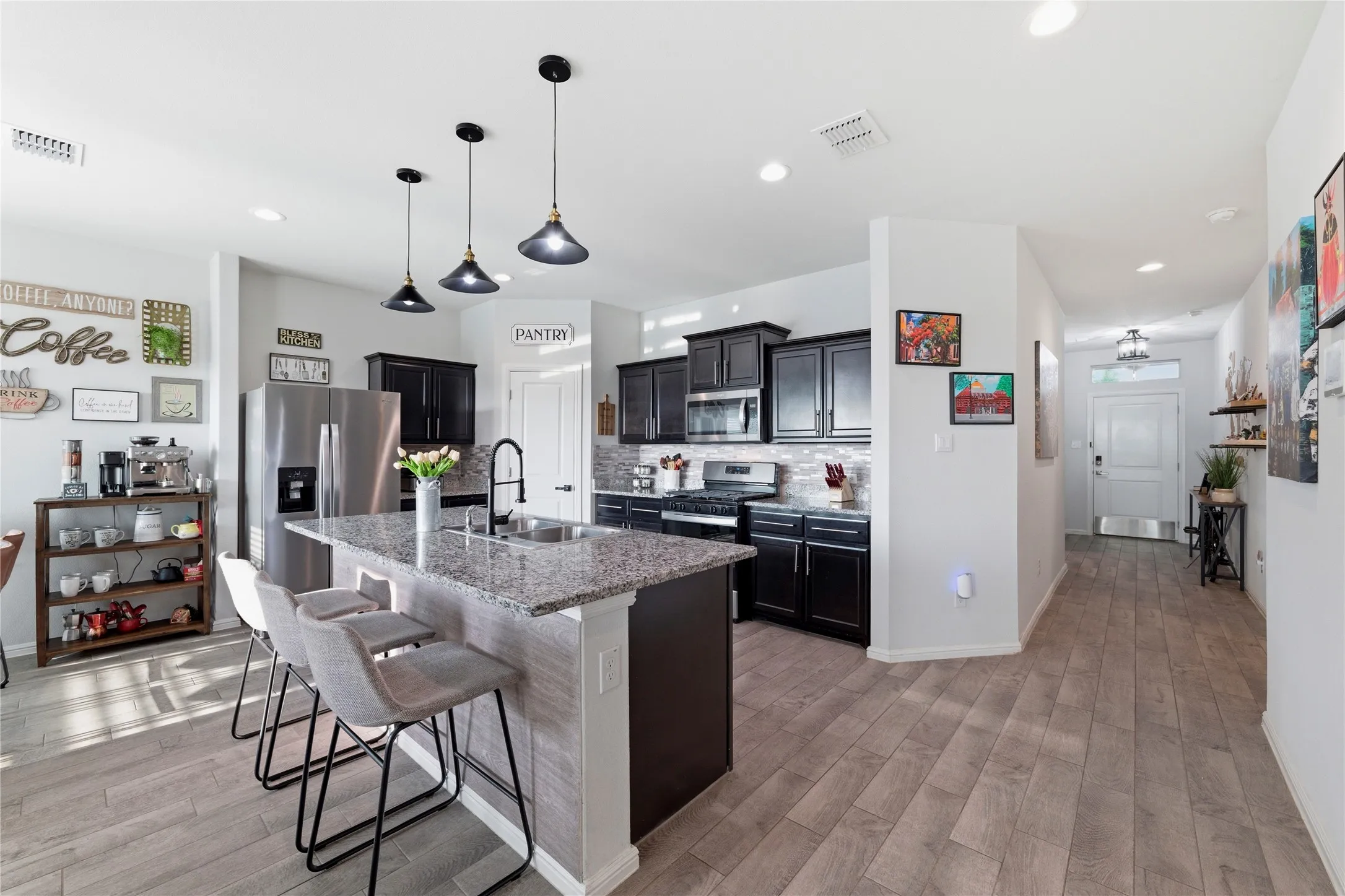 Kitchen featuring a granite-topped island with seating, dark wood cabinetry, stainless steel appliances, and a tile backsplash
