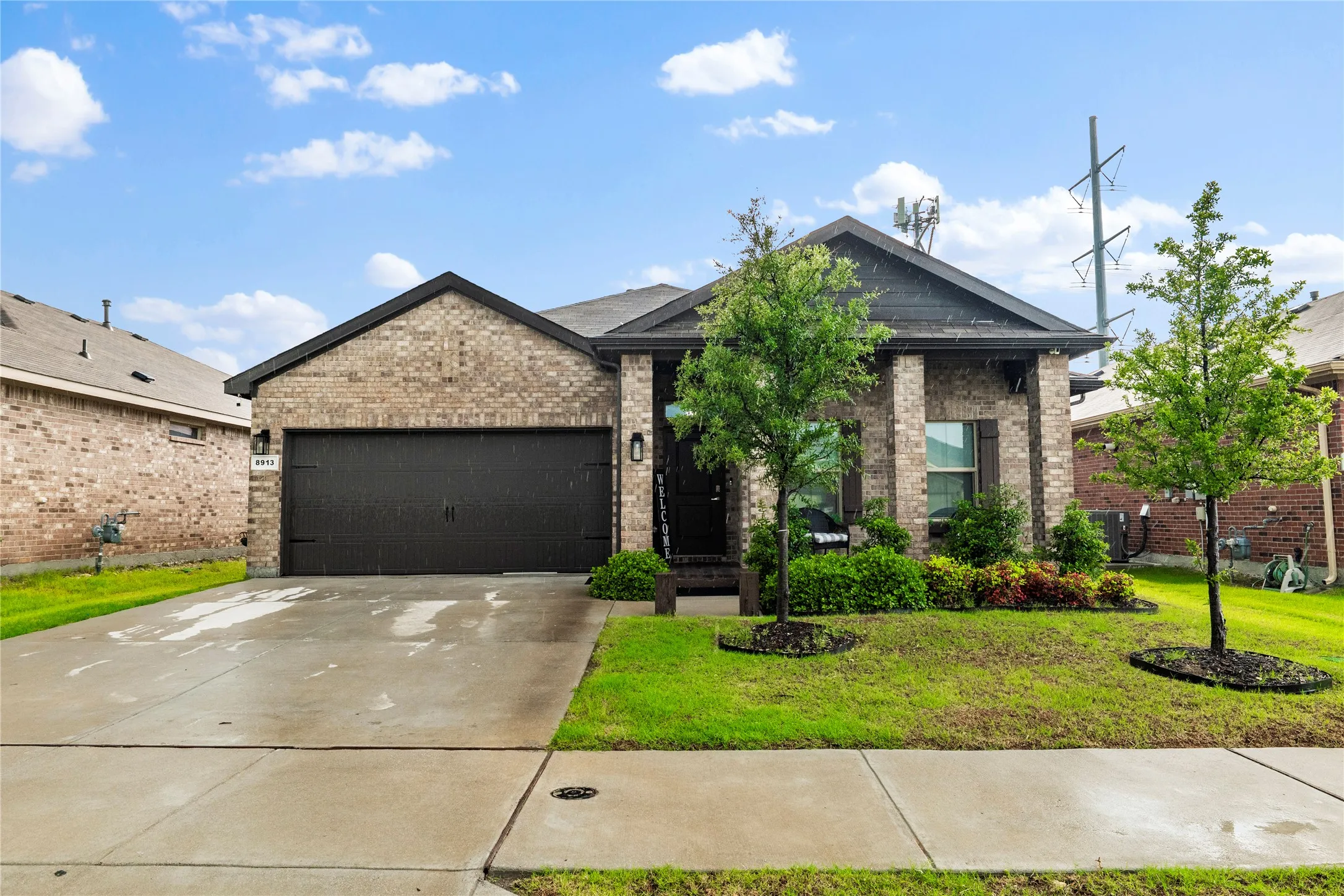 Brick facade home featuring a two-car garage, concrete driveway, and covered entry