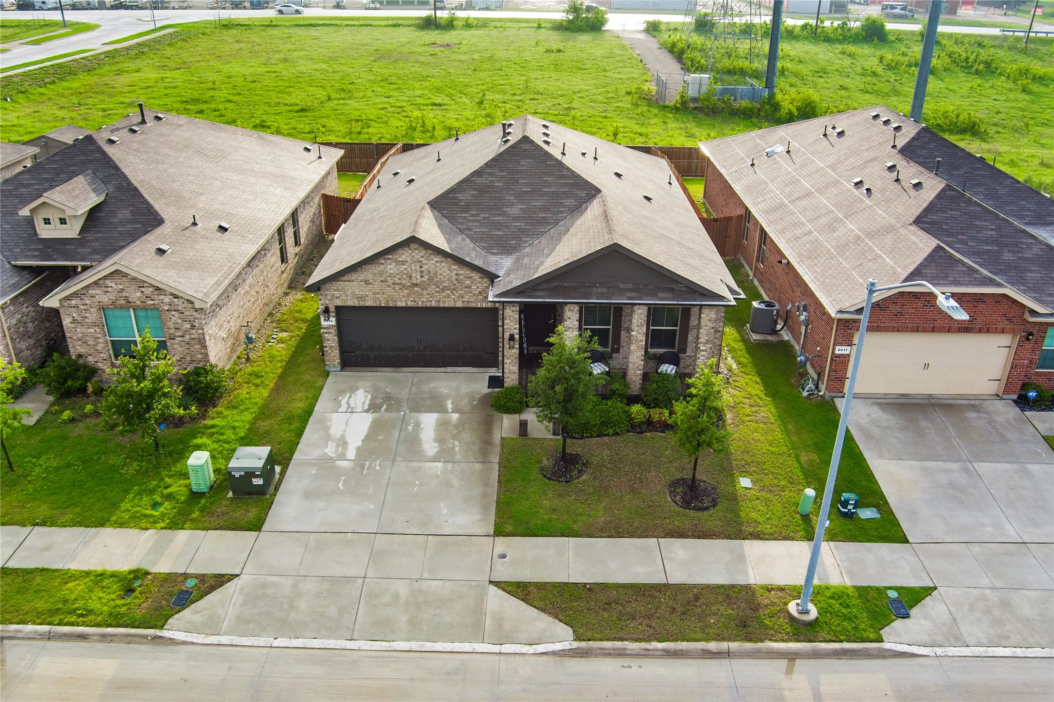Brick-front home featuring an attached garage, paved driveway, and mature landscaping