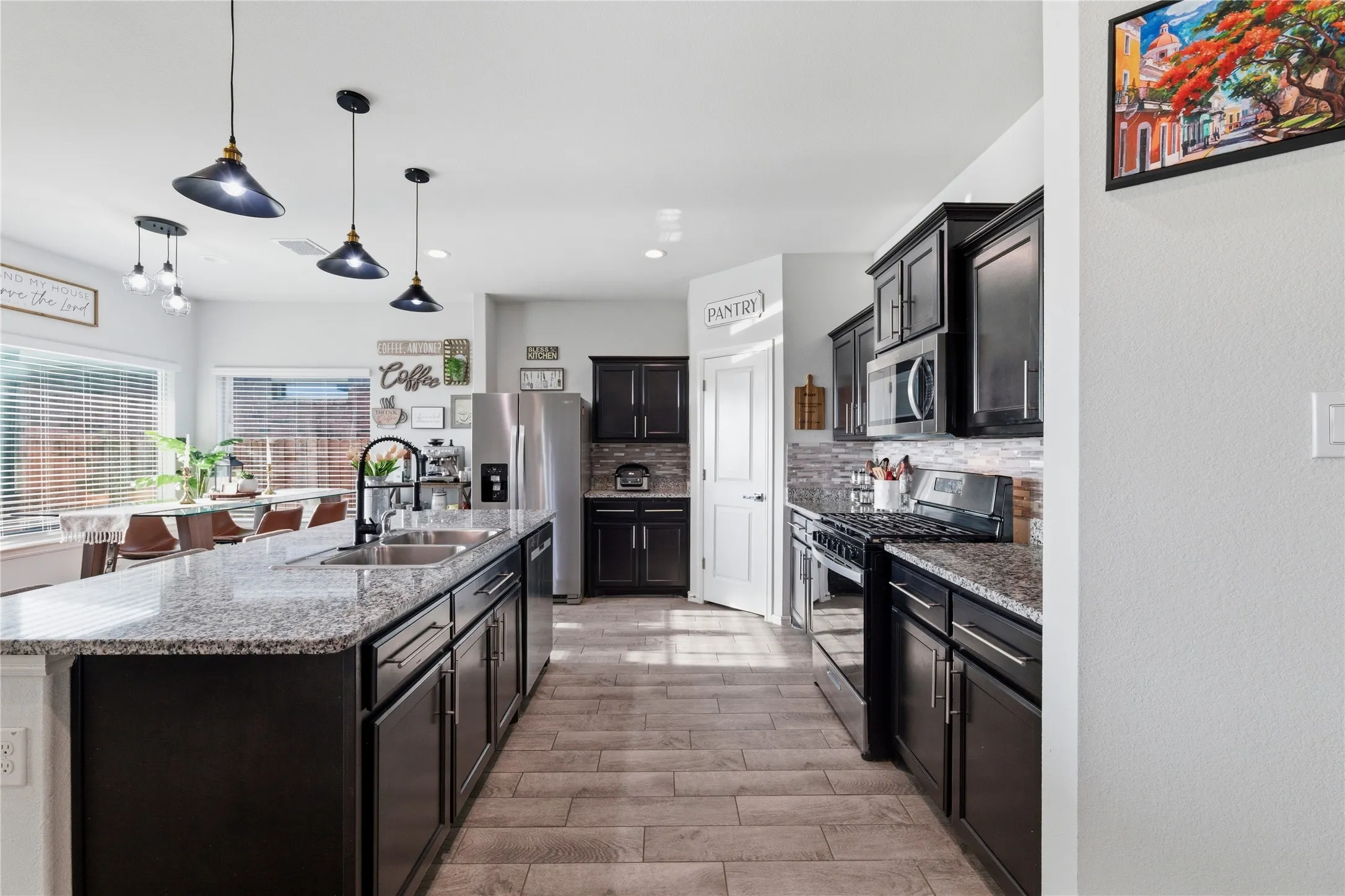 Spacious kitchen featuring dark wood cabinetry, granite countertops, tile backsplash, and stainless steel appliances