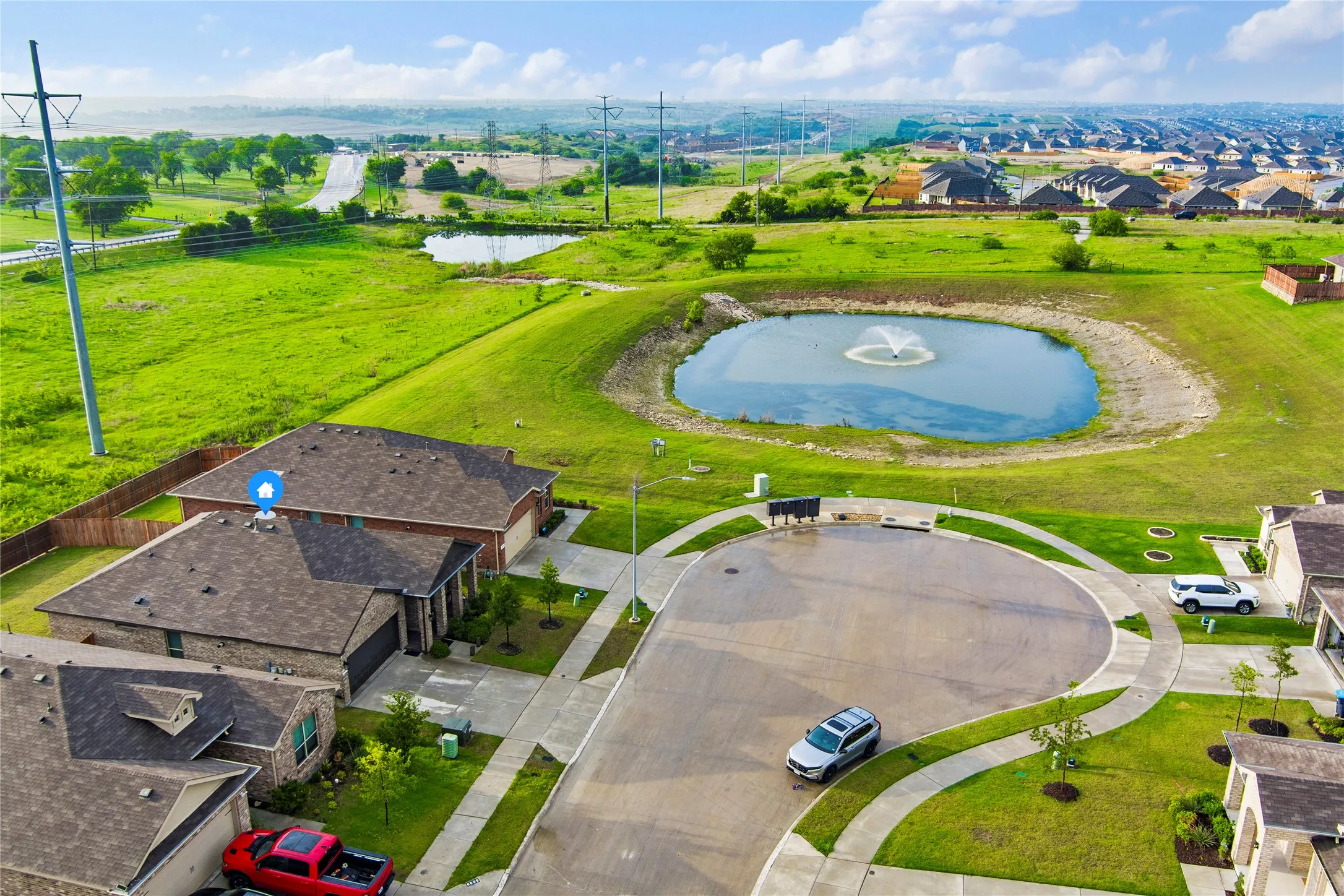 Aerial perspective showcasing a cul-de-sac and a nearby pond with a water fountain feature
