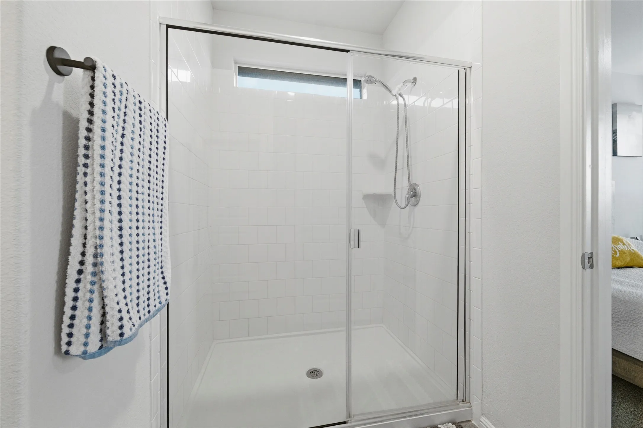 Walk-in shower featuring subway tile surround, clear glass enclosure, and an integrated shelf