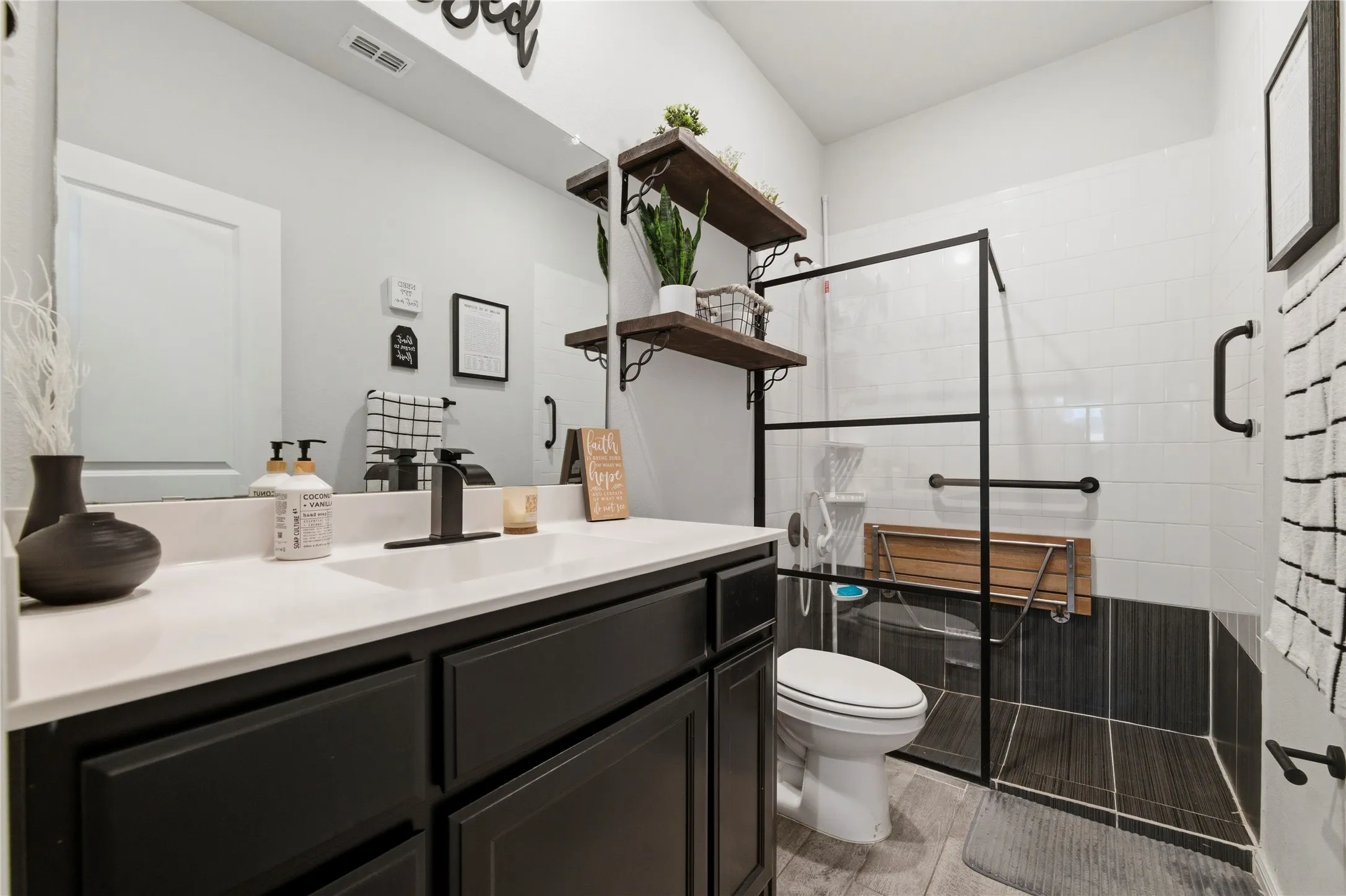Modern bathroom featuring a single vanity with a white countertop and dark cabinetry, an integrated sink, and a matte black faucet
